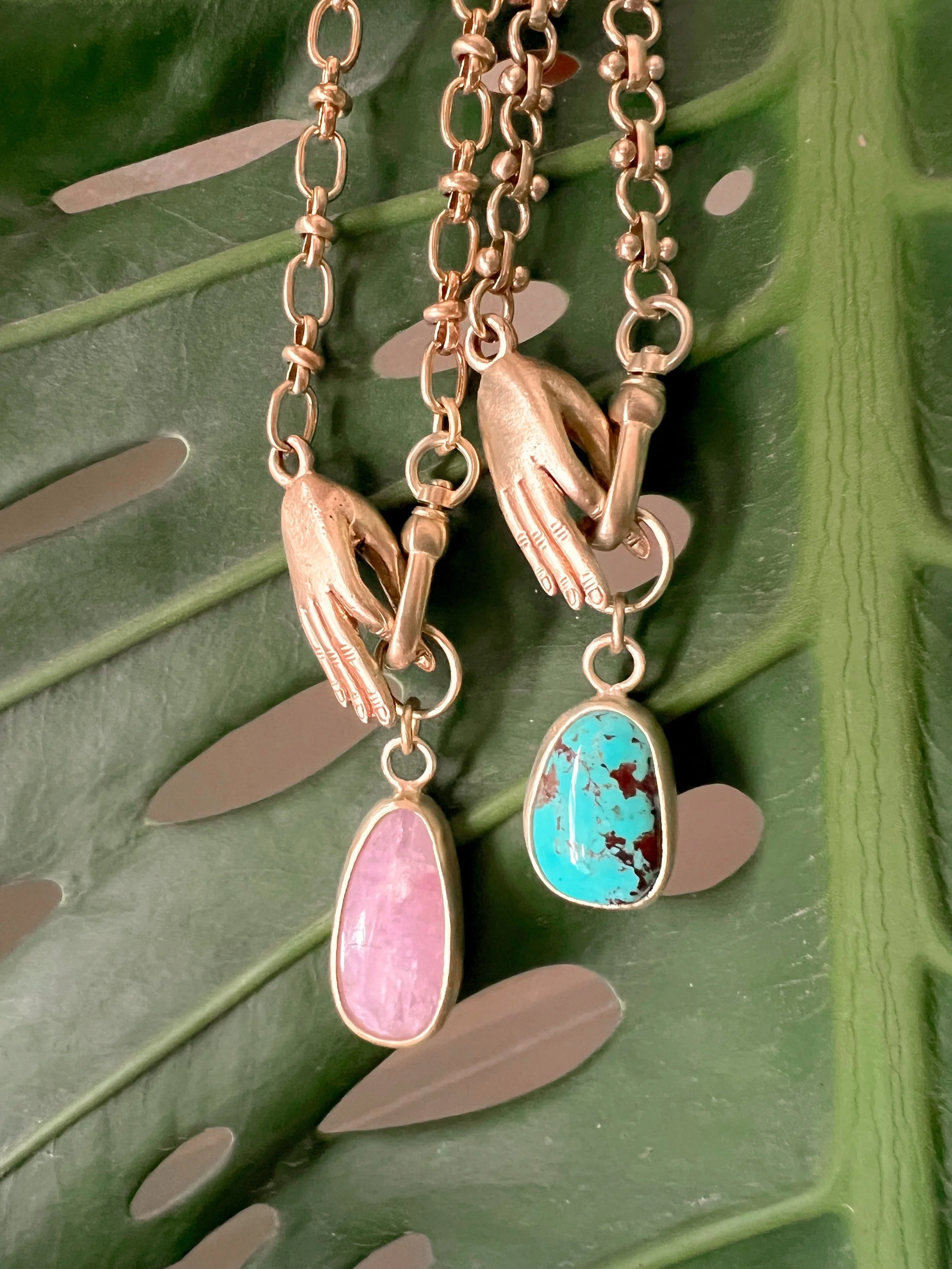 A smooth, natural gemstone cabochon set in a brass pendant on a brass chain.