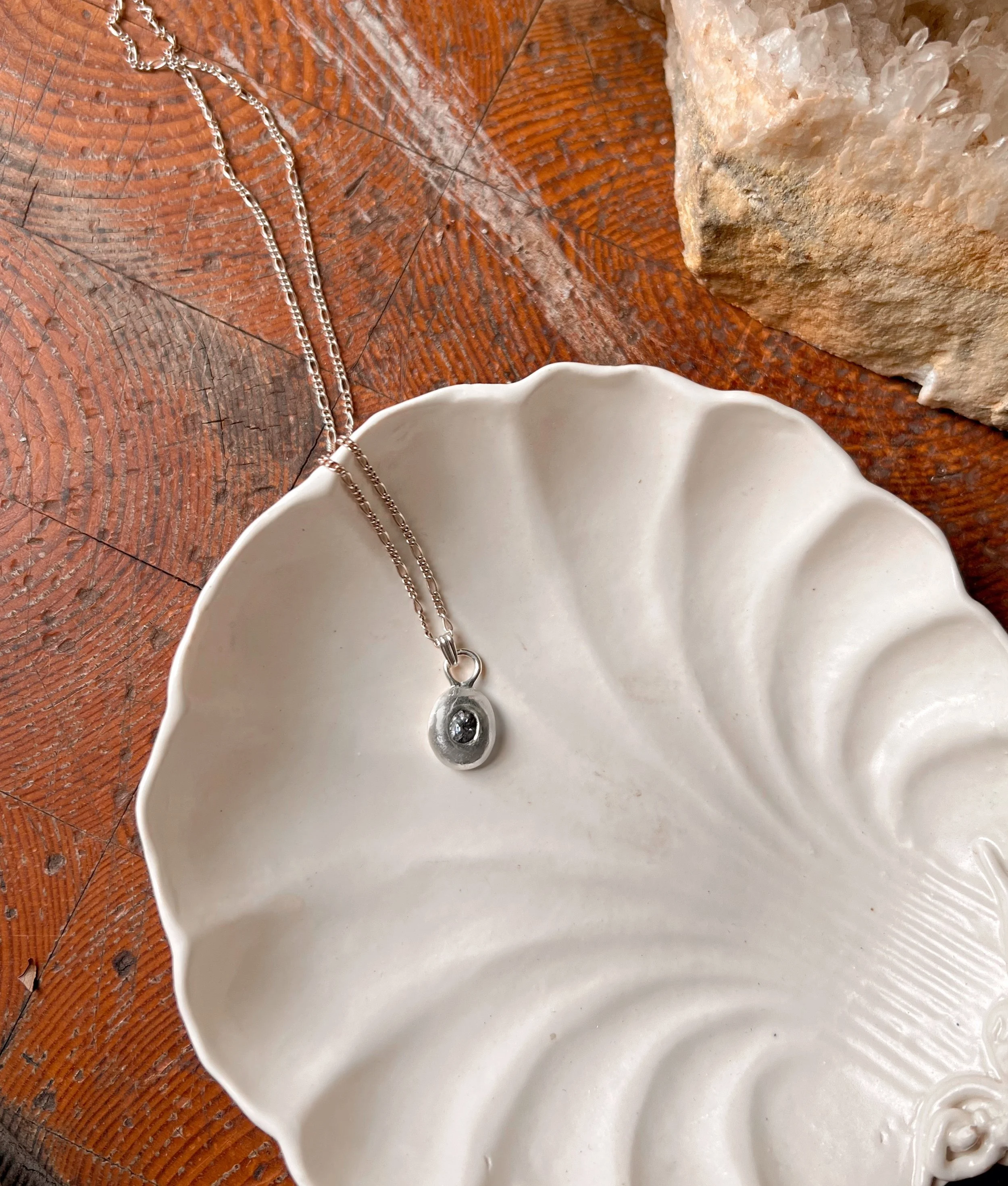 A recycled sterling silver blob, with a faceted gemstone in the center.