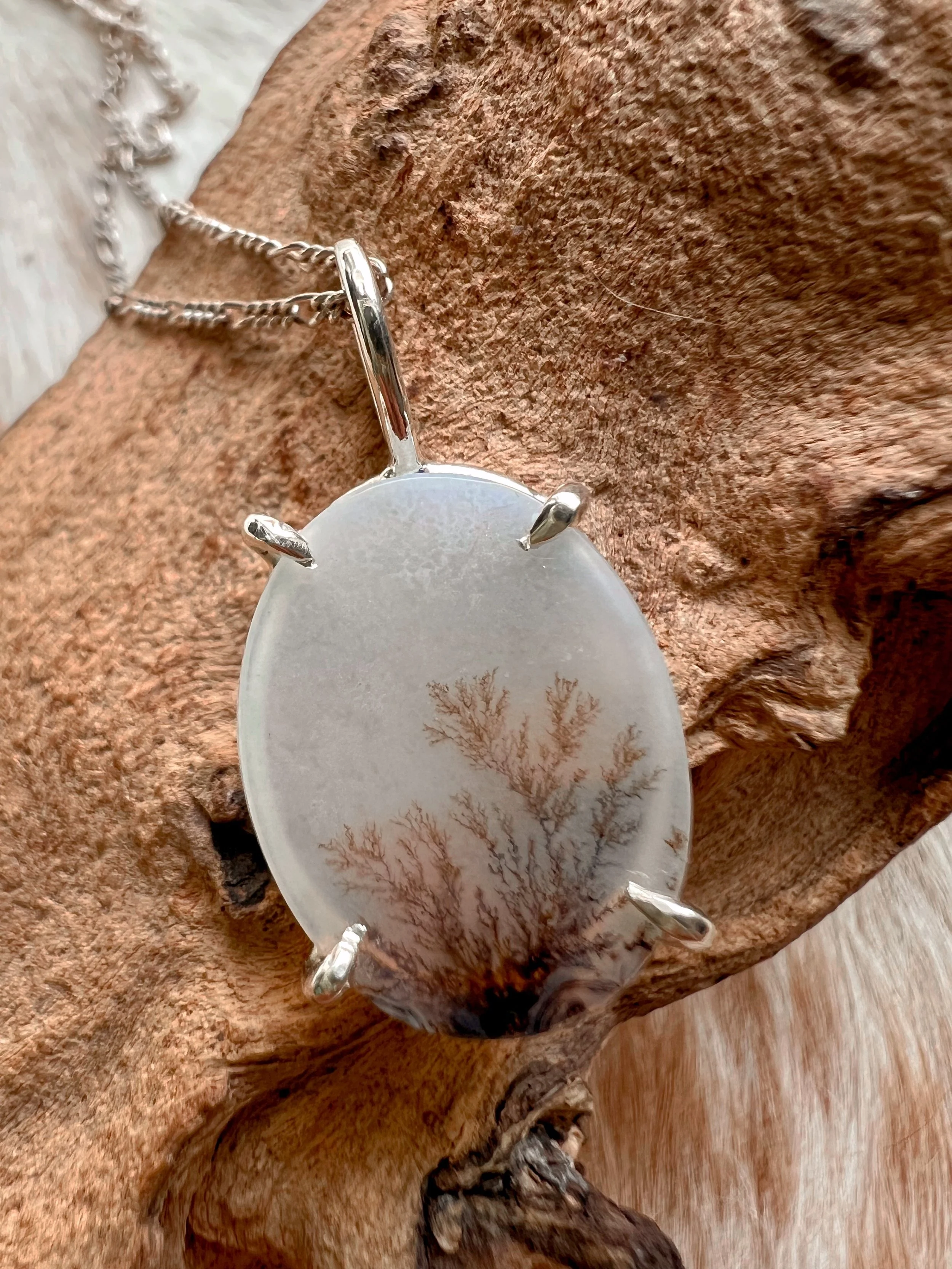 A smooth, natural gemstone cabochon set in a Sterling silver pendant on a sterling silver chain