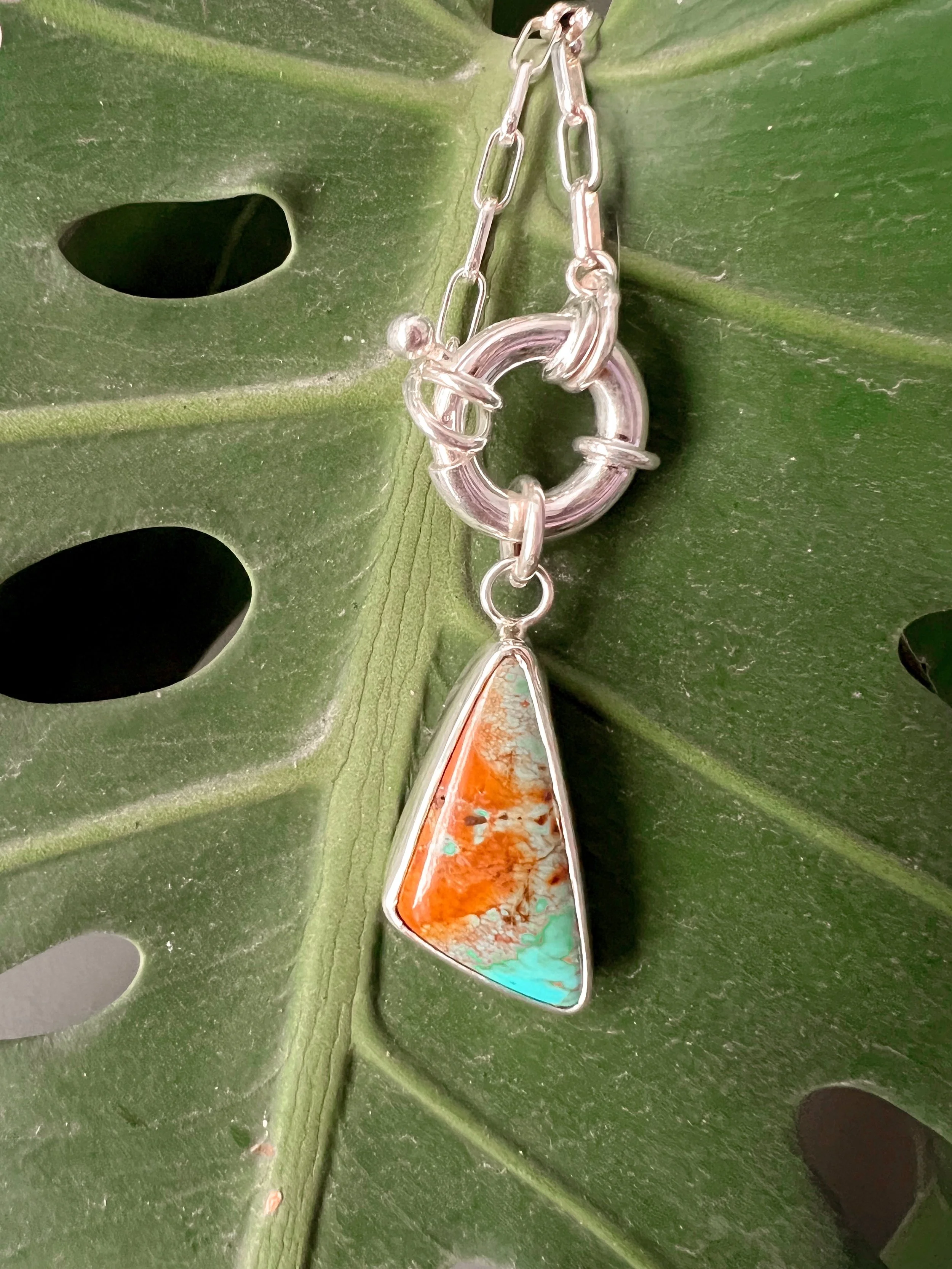 A smooth, natural gemstone cabochon set in a Sterling silver pendant on a sterling silver chain