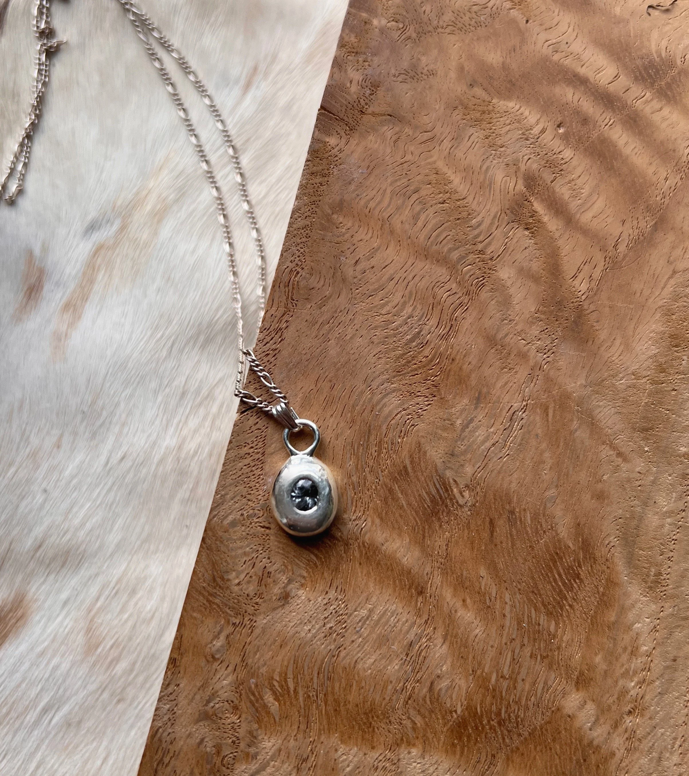 A recycled sterling silver blob, with a faceted gemstone in the center.