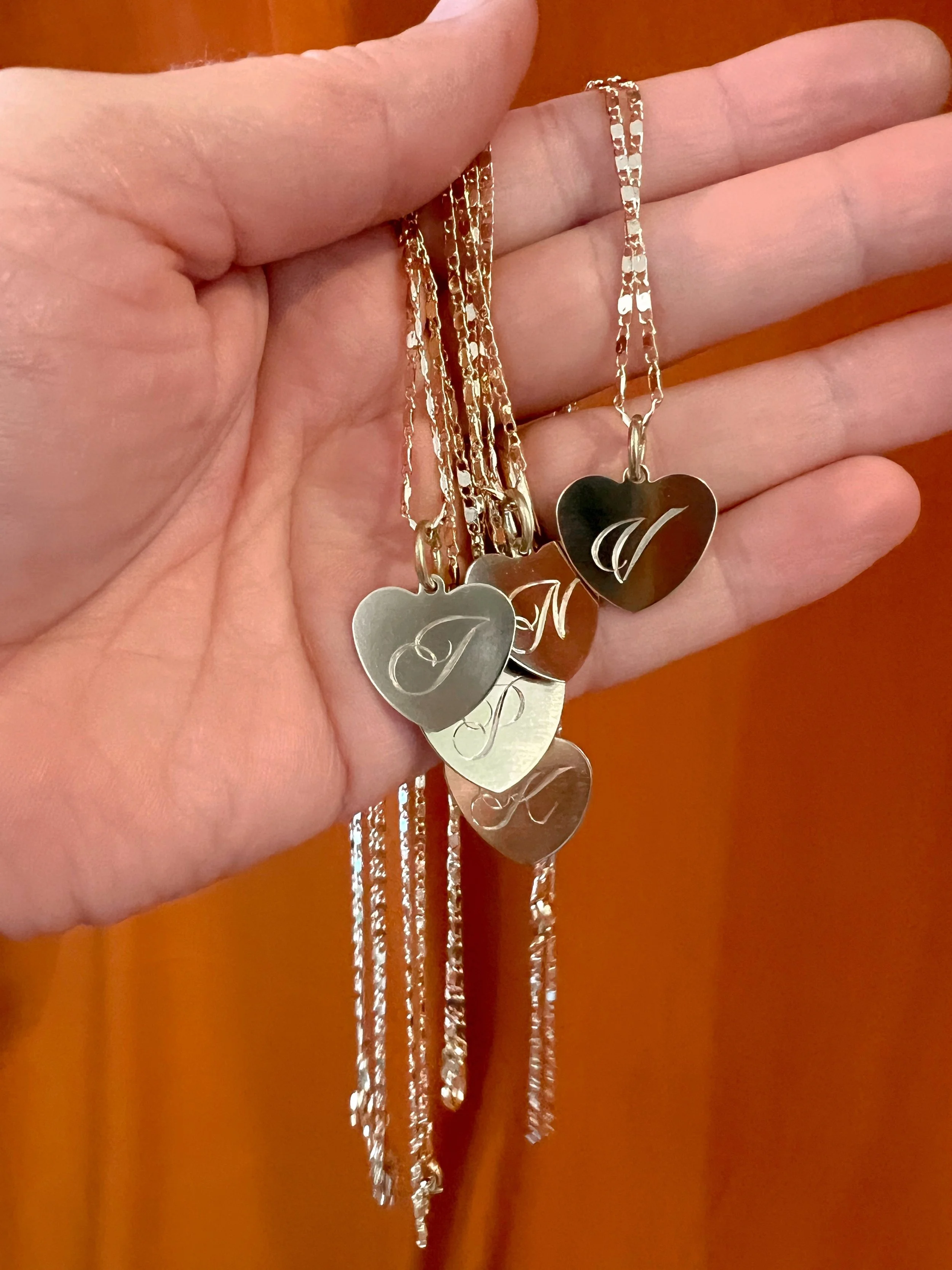 Personalized hand engraved script initial on a small brass heart