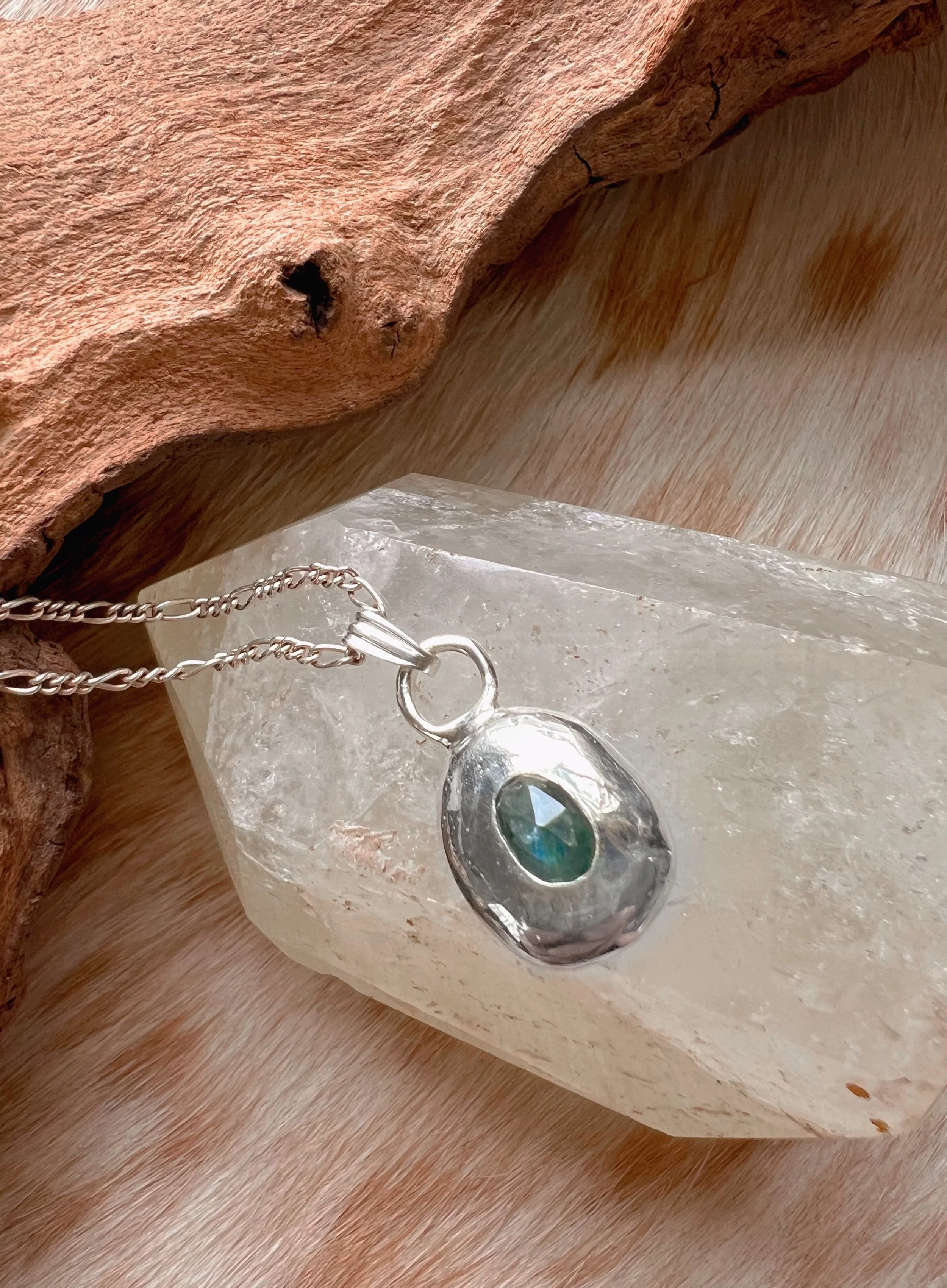 A recycled sterling silver blob, with a faceted gemstone in the center.