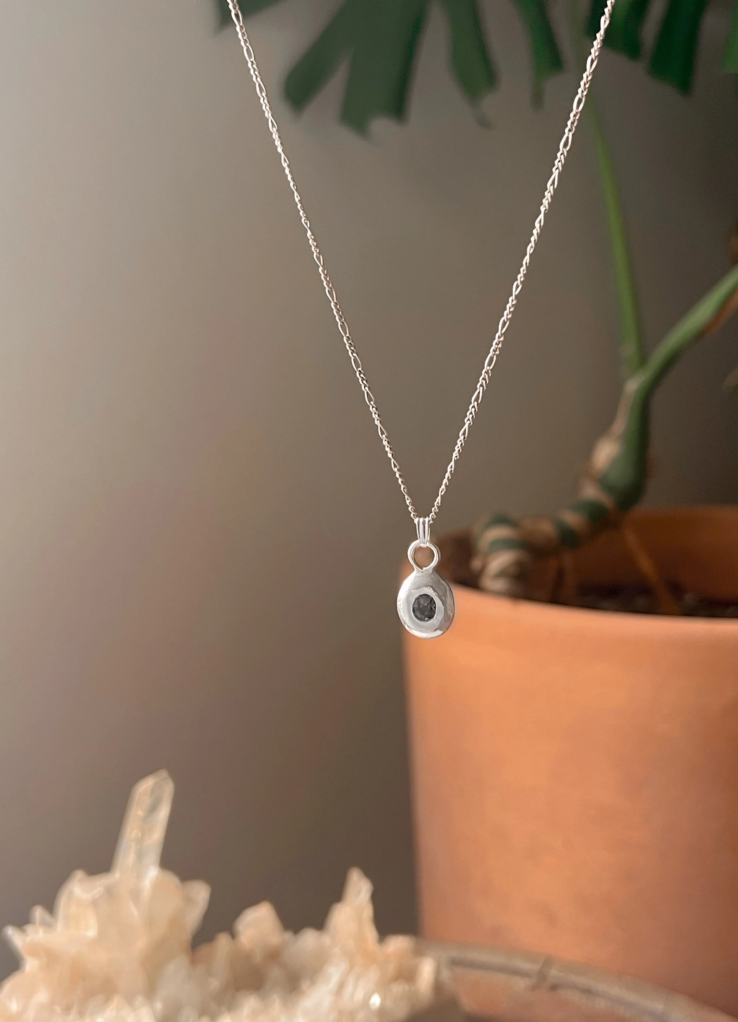 A recycled sterling silver blob, with a faceted gemstone in the center.