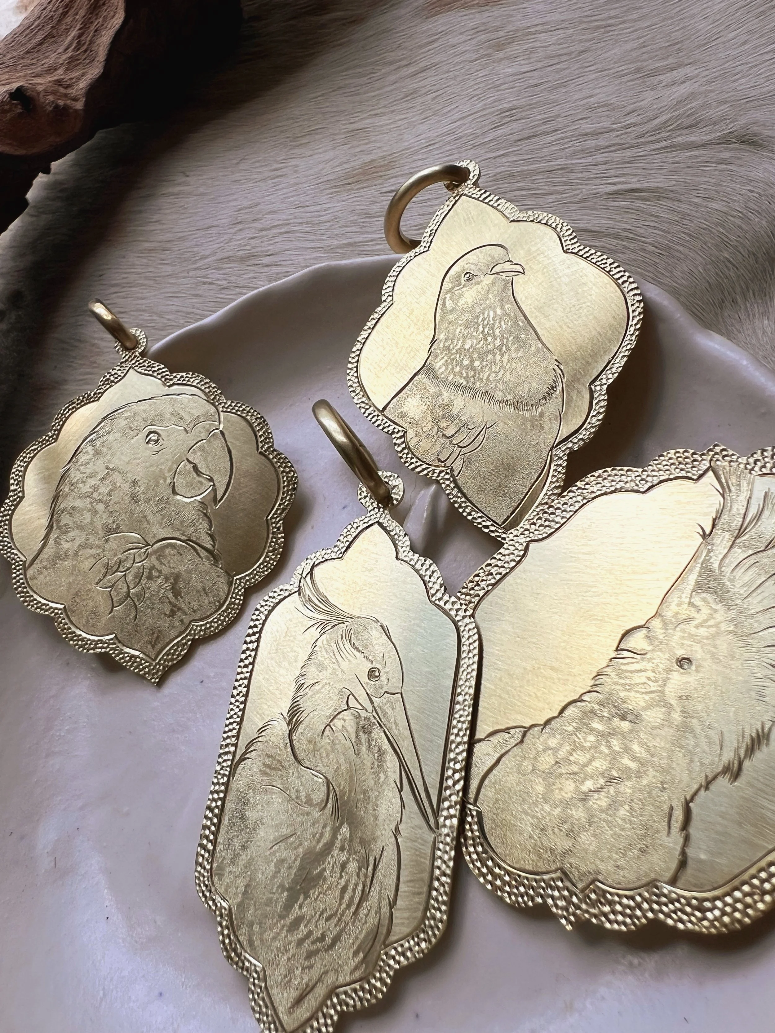 Detailed hand-engraved brass pendant featuring a bird portrait