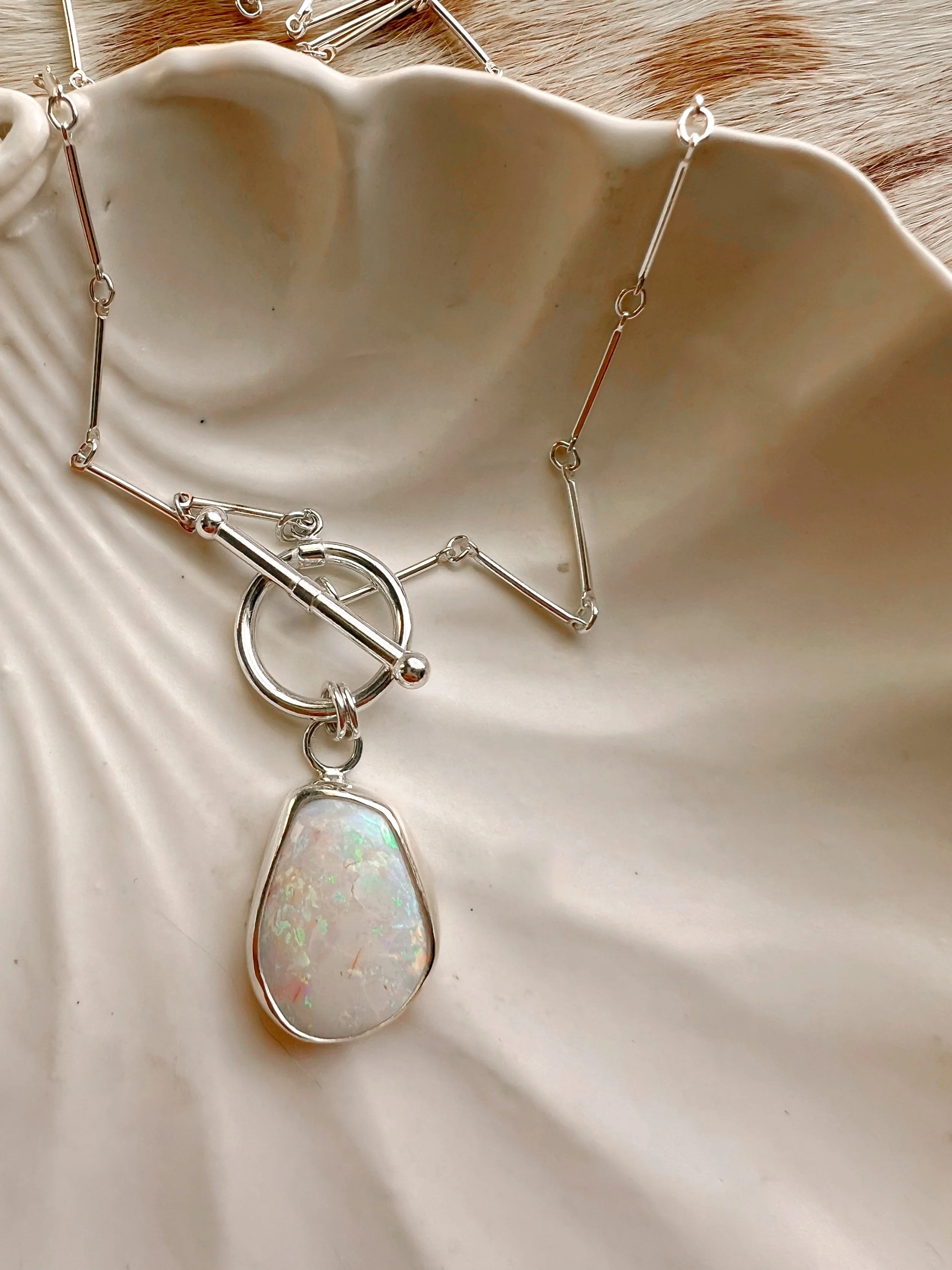 A smooth, natural gemstone cabochon set in a Sterling silver pendant on a sterling silver chain