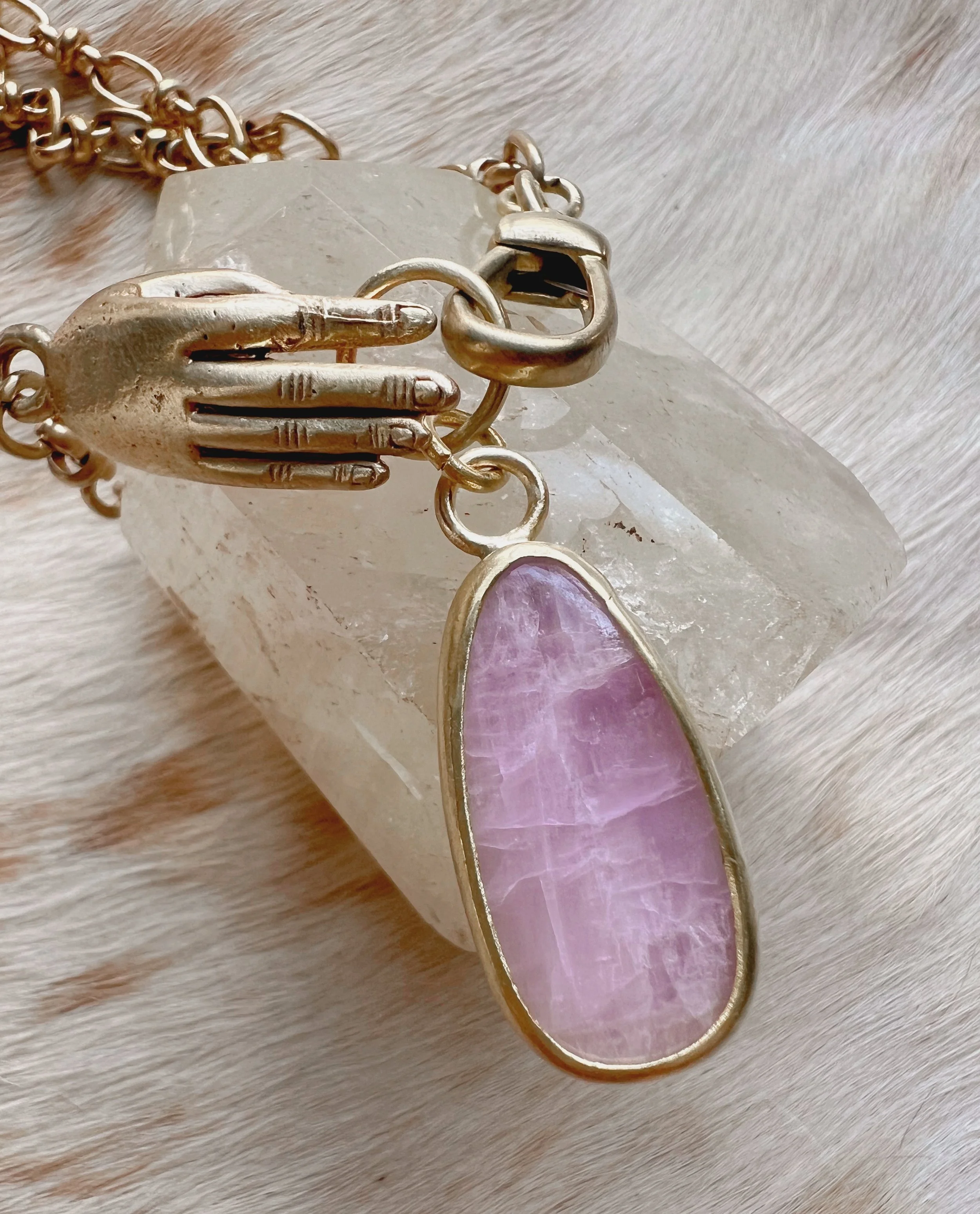 A smooth, natural gemstone cabochon set in a brass pendant on a brass chain.