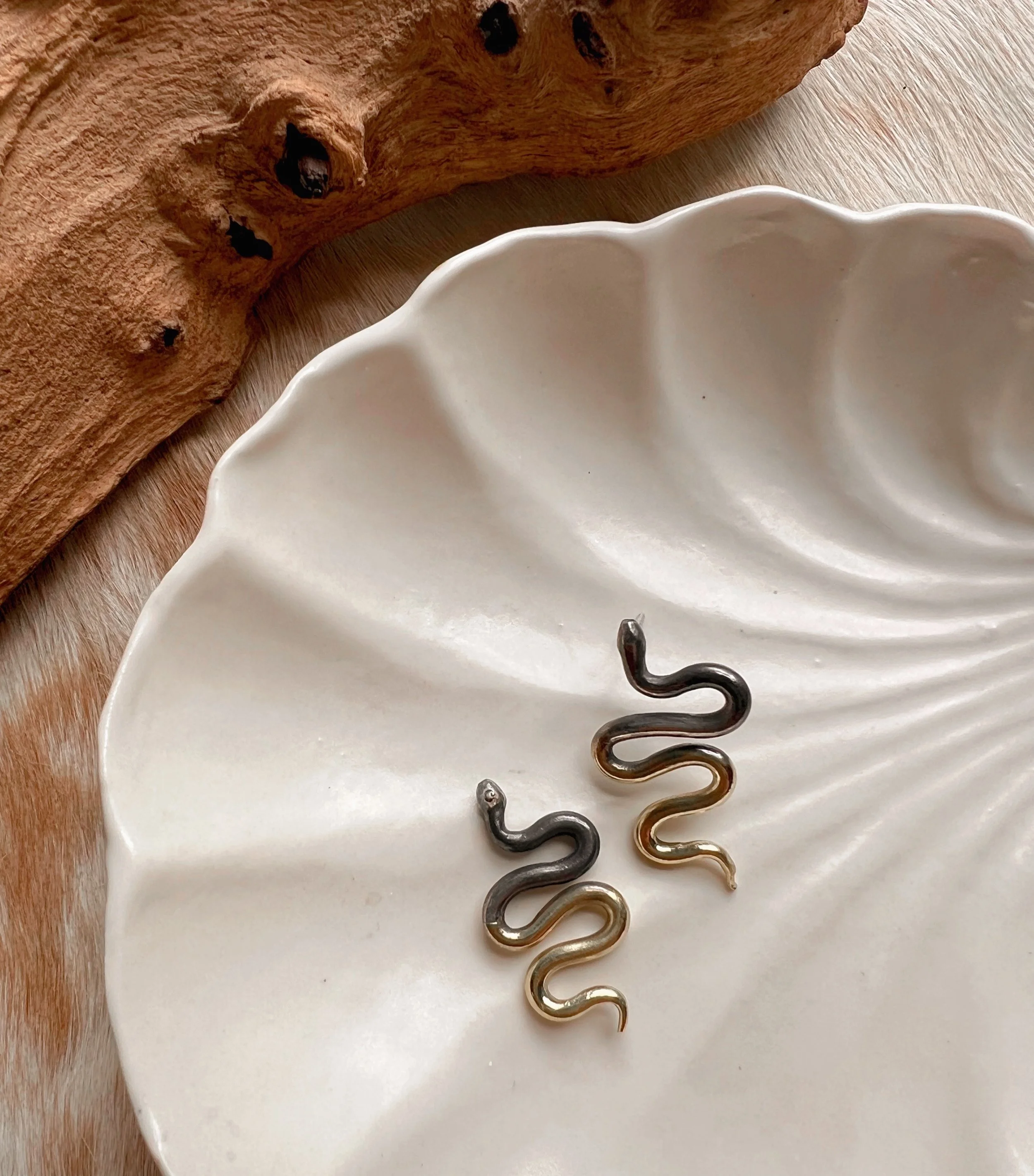 A pair of snake earrings made of oxidized silver fading to brass with sterling silver posts and backs