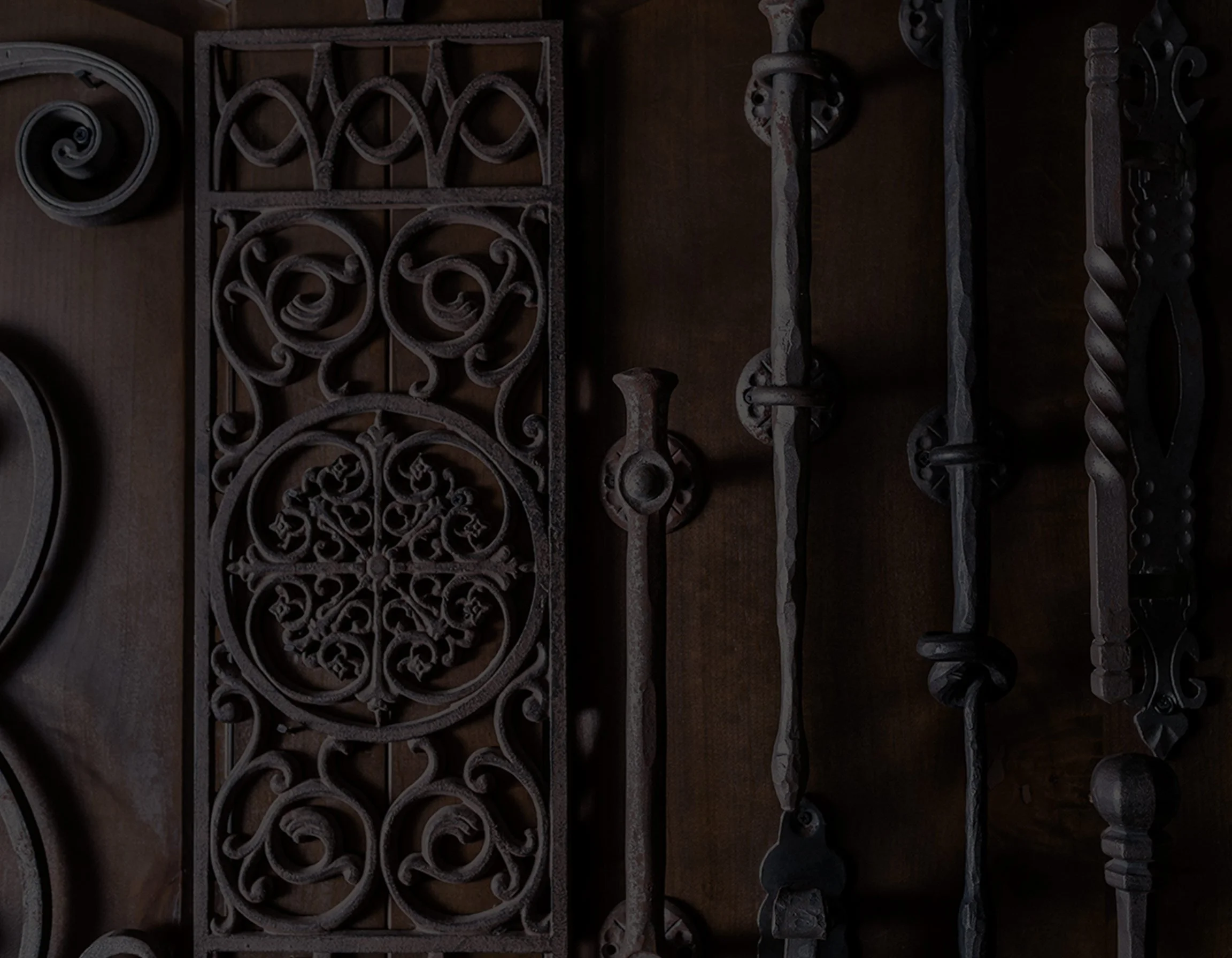 Collection of artisan wrought iron decorative pieces on a wooden surface, symbolizing work done for Architectural Justice. Created by Clarke Creative.