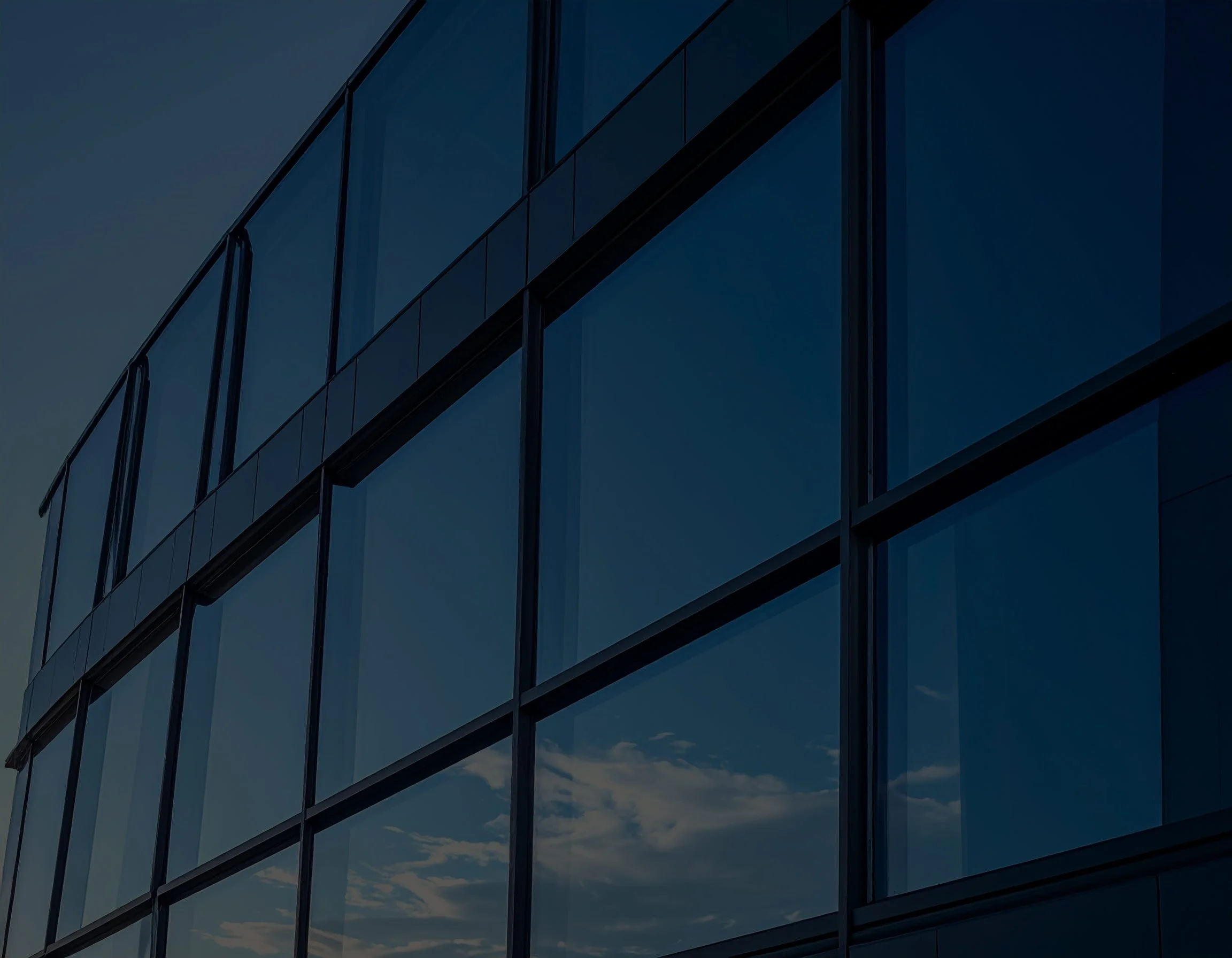 Modern glass building with reflections of clouds and sky on its windows, symbolizing work design done for Dayton Children's Hospital. Created by Clarke Creative.