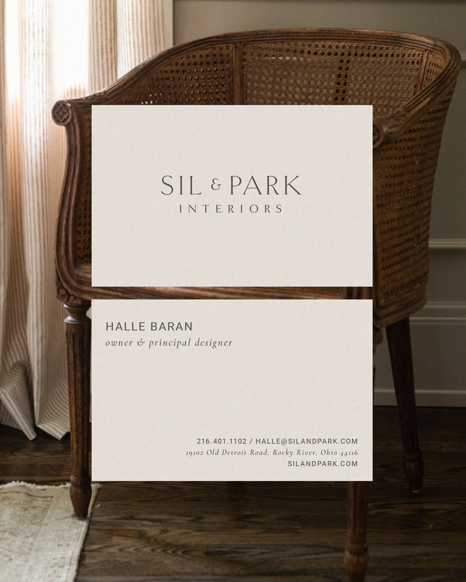 SIL & Park Interiors business card overlayed on a woven cane-back chair. Design created by Clarke Creative.