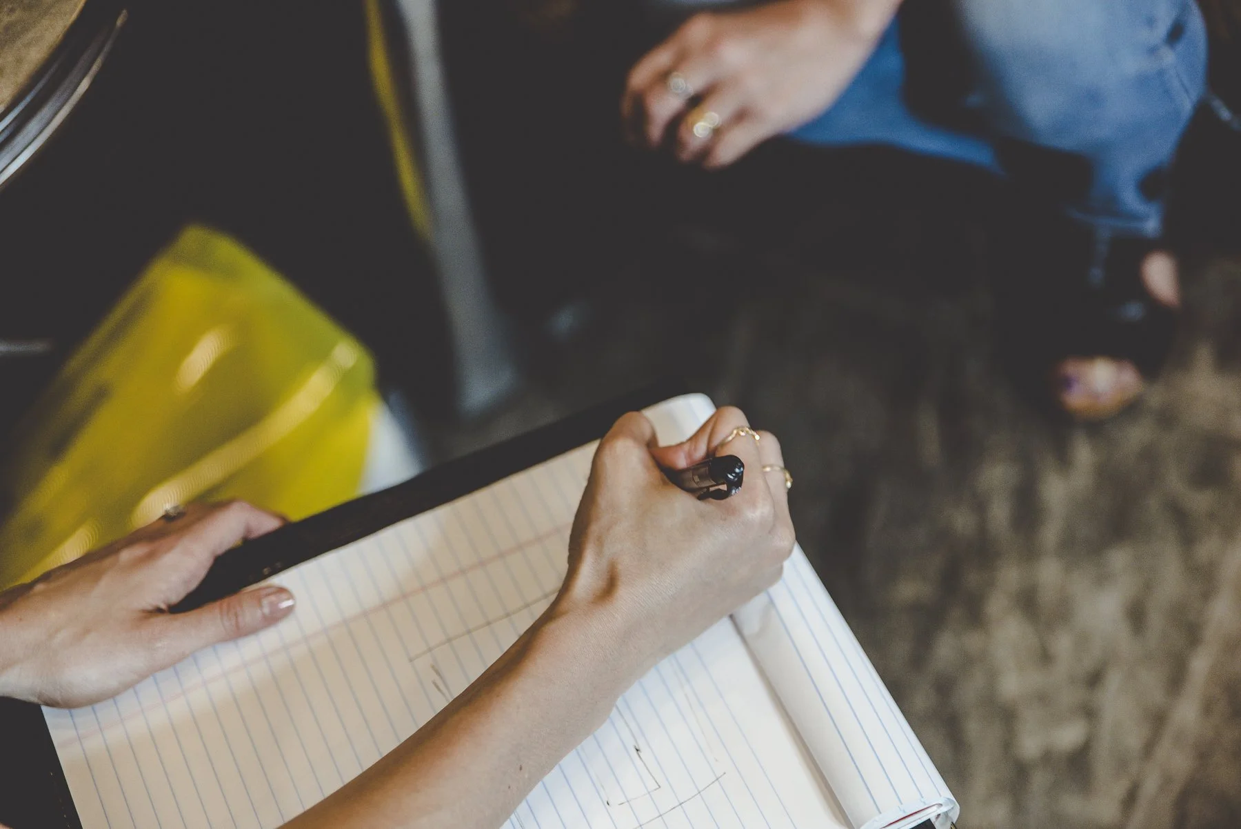 Rachelle Clarke writing in a notebook with a pen, meeting with a client, at her brand strategy studio, Clarke Creative.