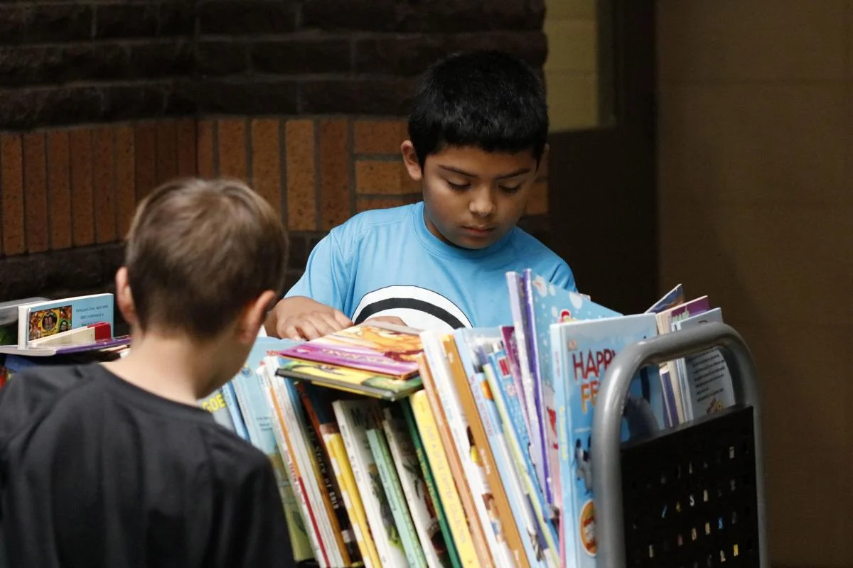 Hoover Elementary first graders Christian Martinez, in back, and Ethan Michael, front, skim through a selection of books to find their choices. Photo by Susan Payne