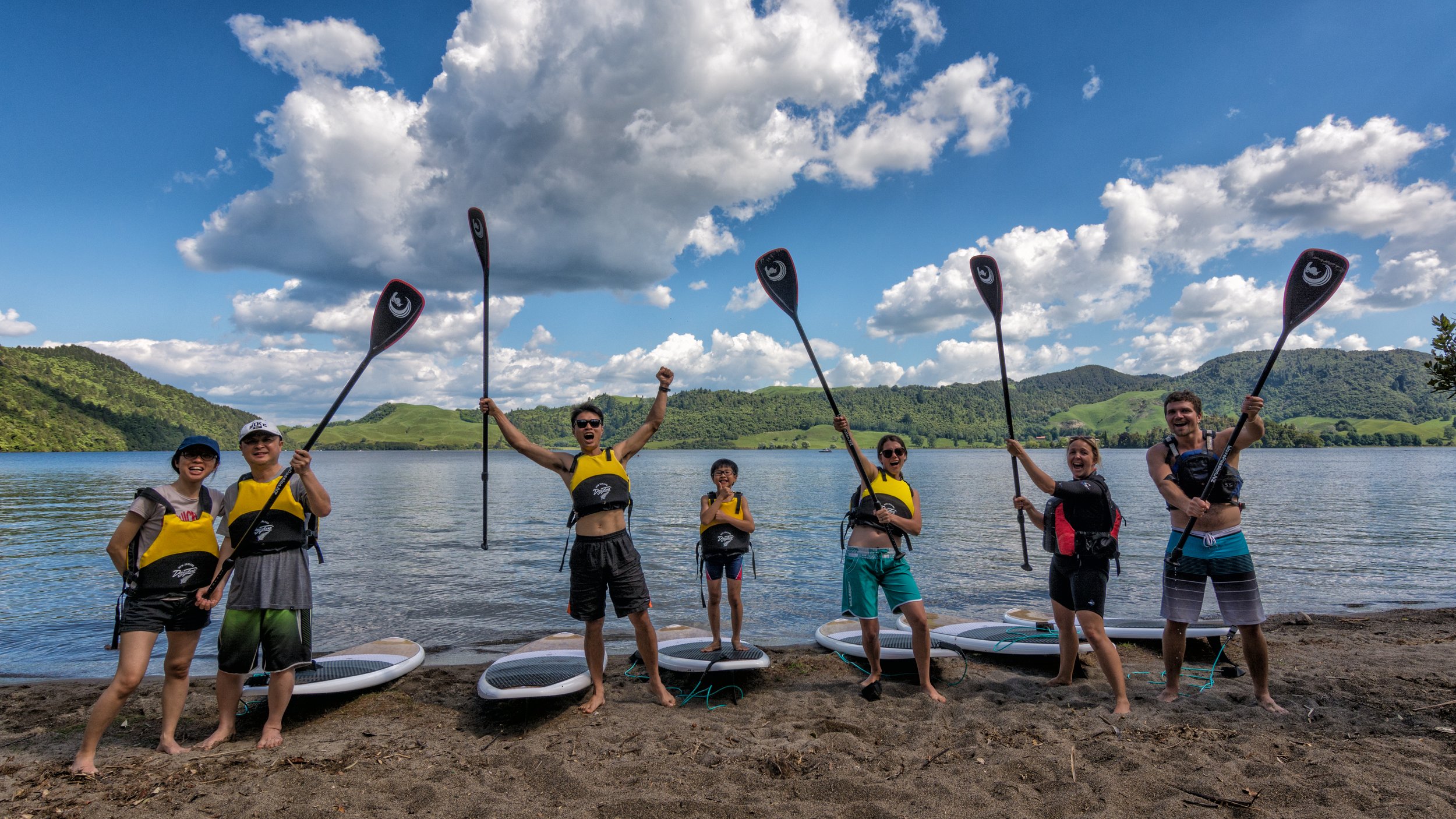 Group Standing on Land With Paddles in Air.jpg