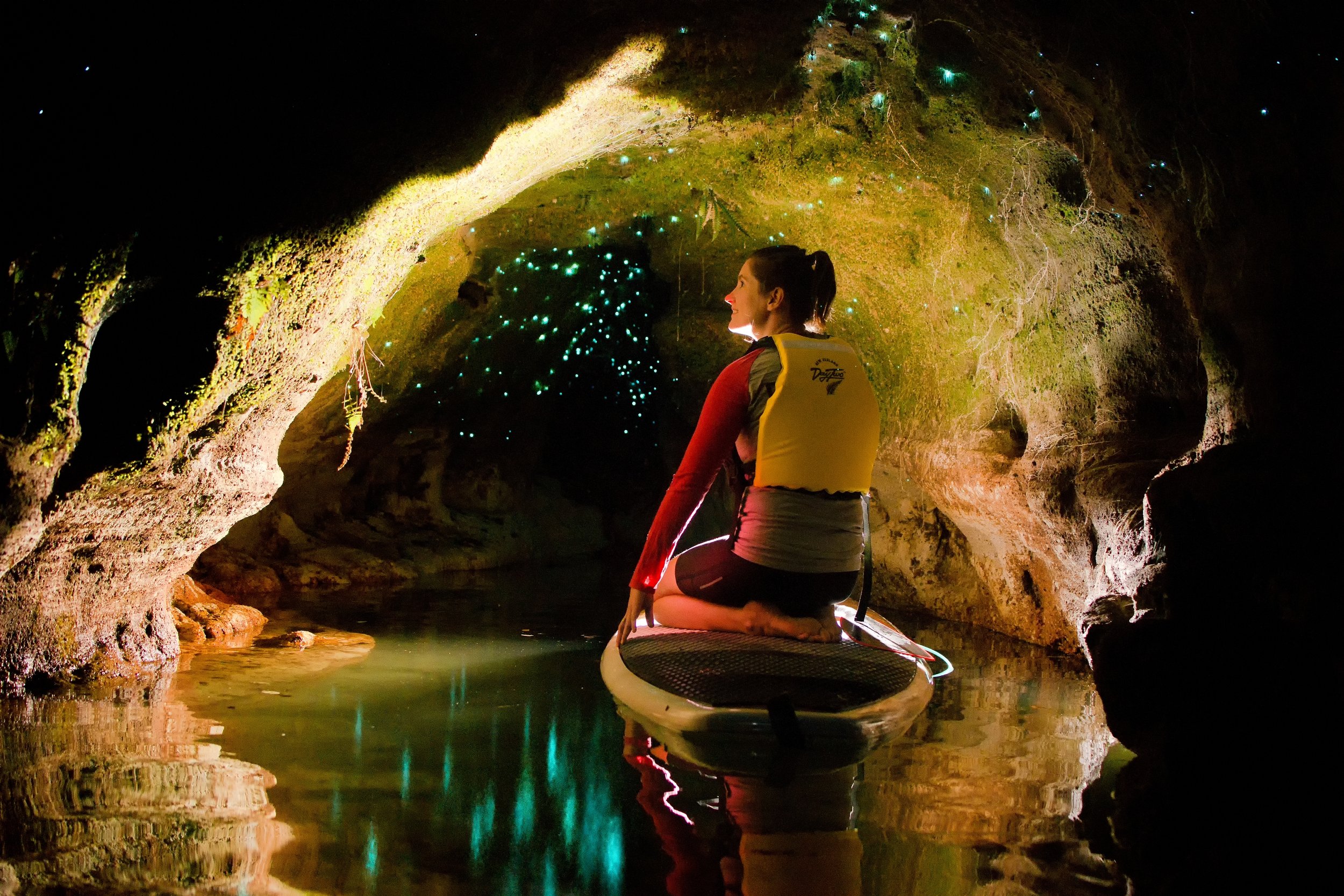 A woman sits on a paddle board in Rotorua NZ gazing at glow worms in an amazing glow worm cave.jpg