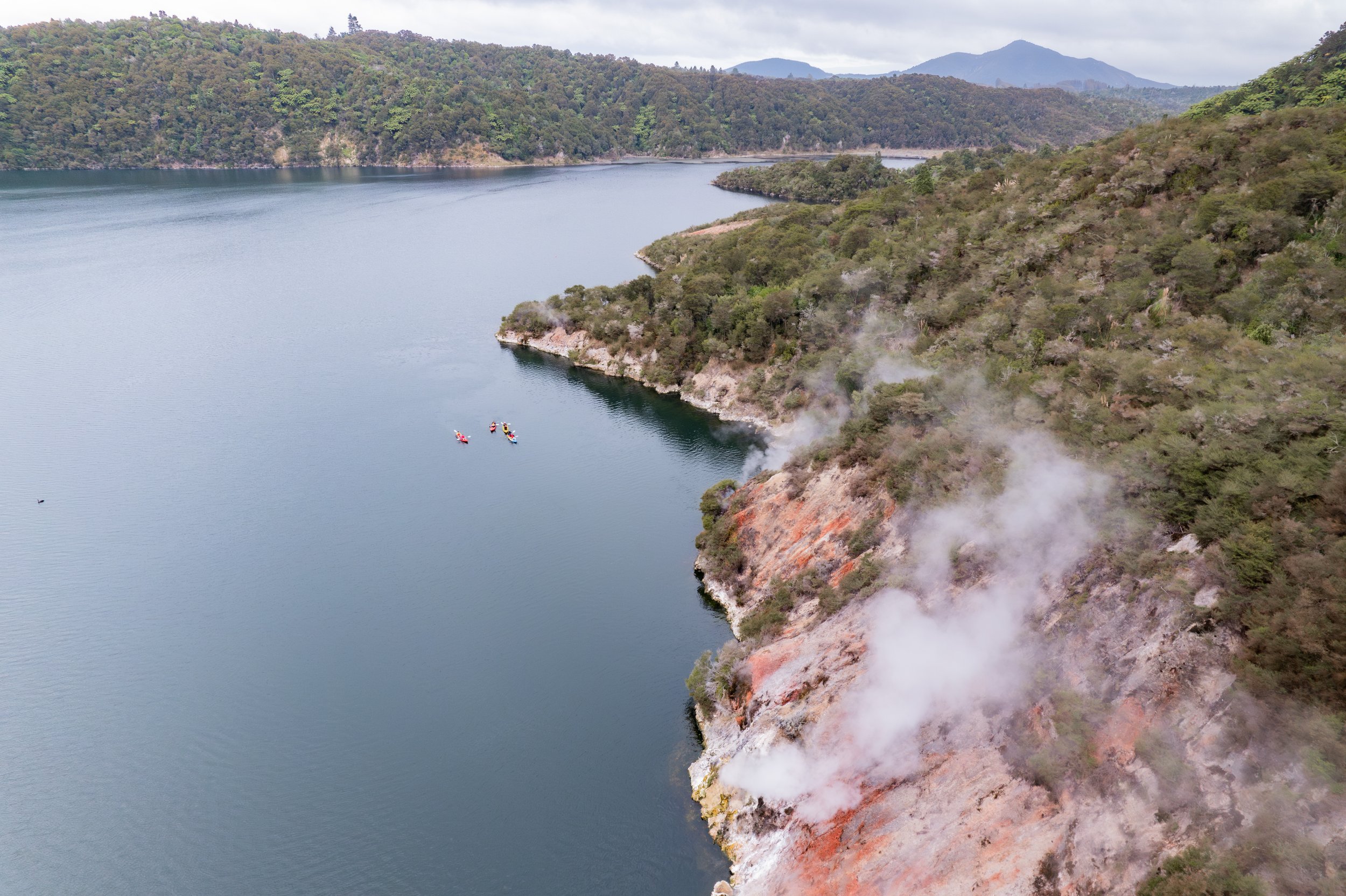 Kayaks on Lake Rotomahana with Native bush & colourful landscapes.jpg
