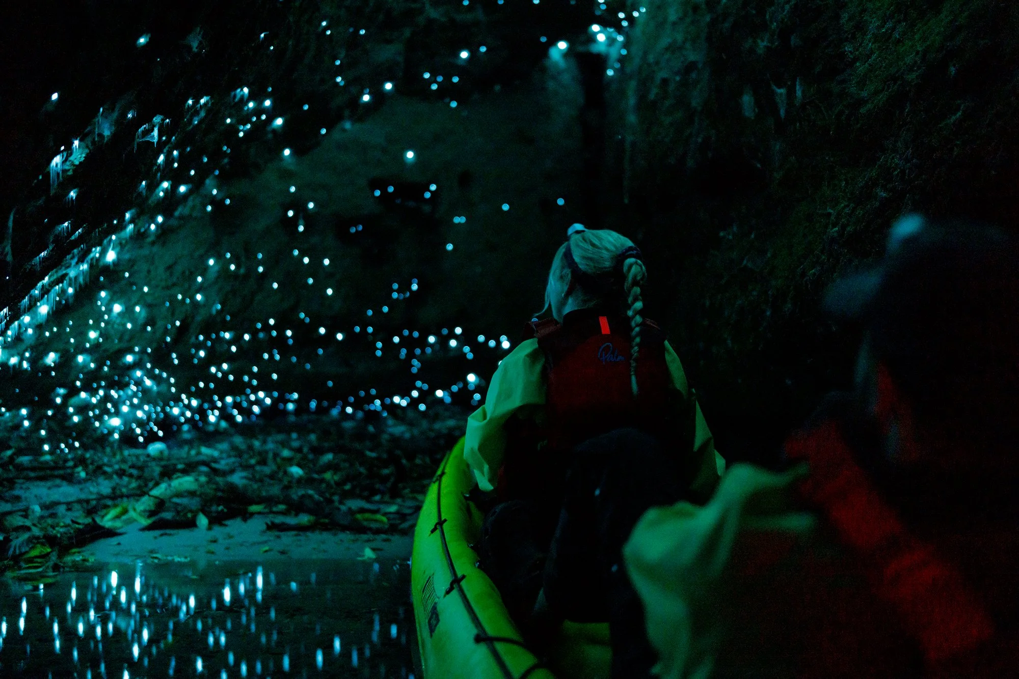 A kayak adventure tour with a kayaker in a cave covered with glow worms