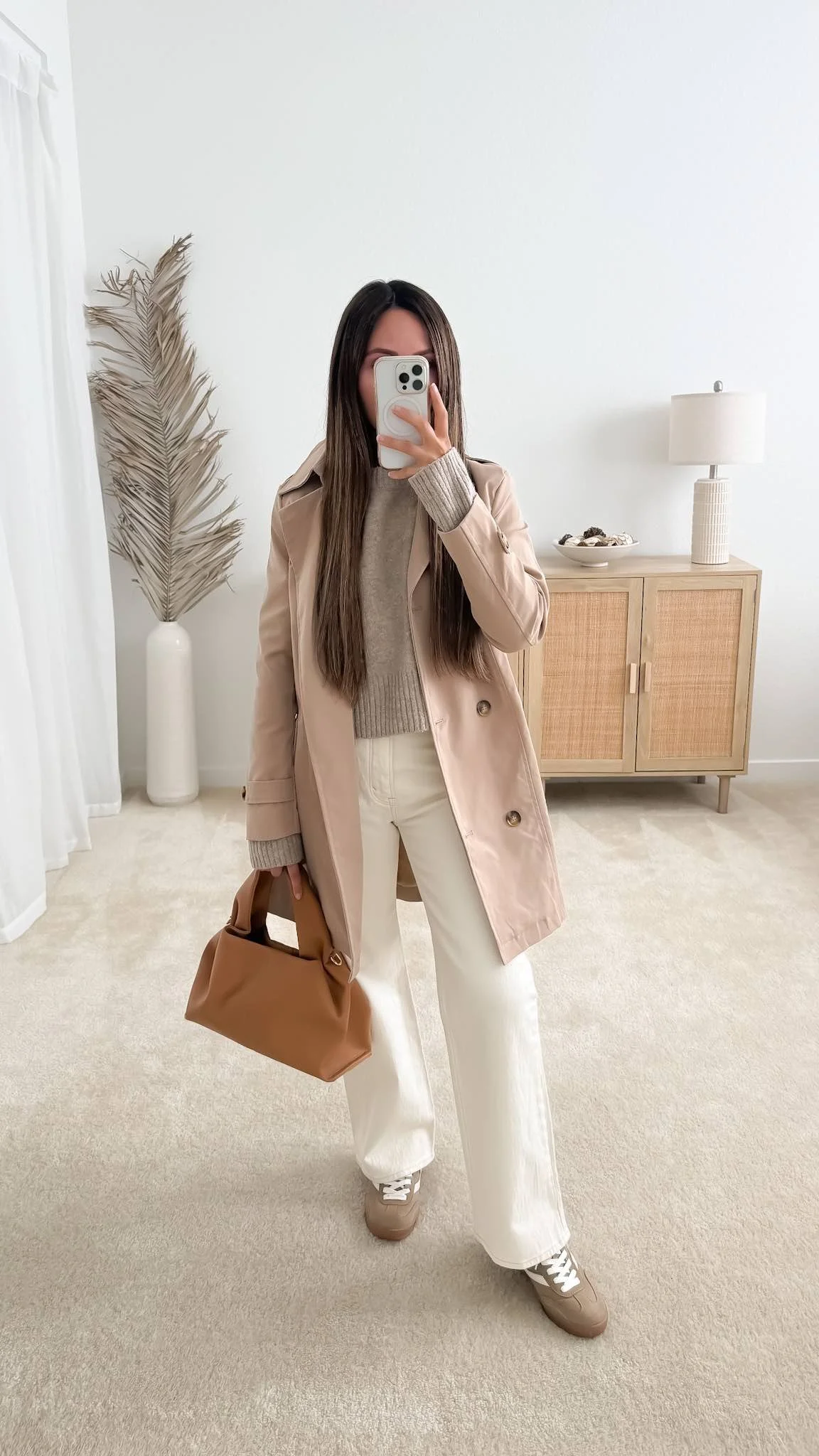 Beige trench coat outfit with a taupe knit sweater, white wide-leg jeans, and taupe sneakers.