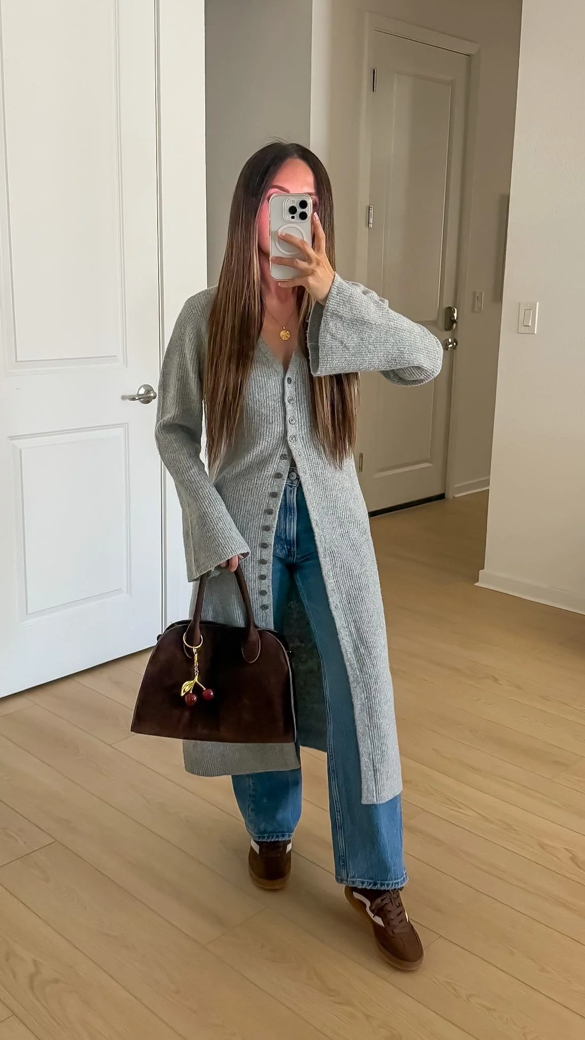 Long gray cardigan styled with wide leg jeans, brown sneakers, and a brown handbag