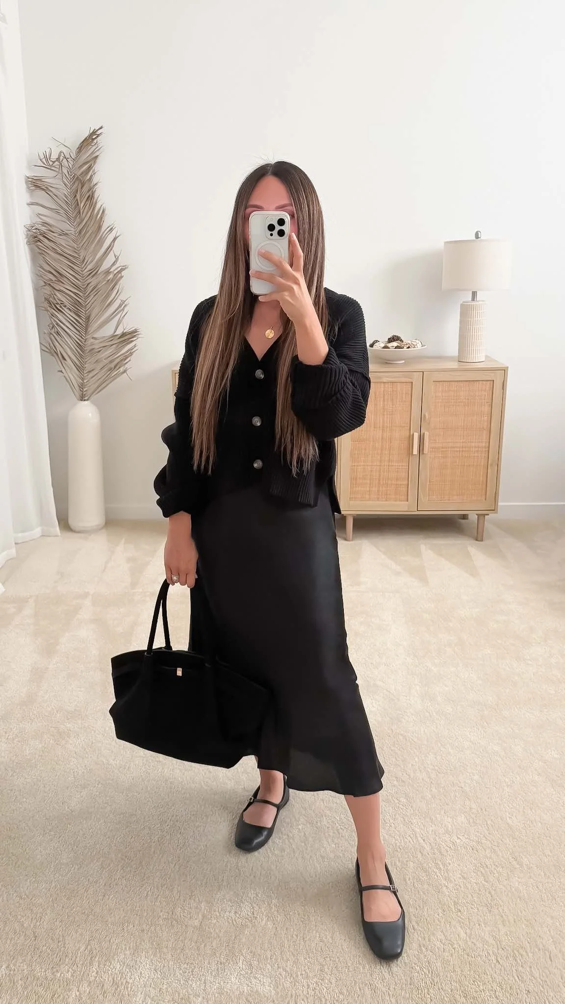 Chic fall date night outfit with a black cardigan, satin midi skirt, ballet flats, and a black suede tote