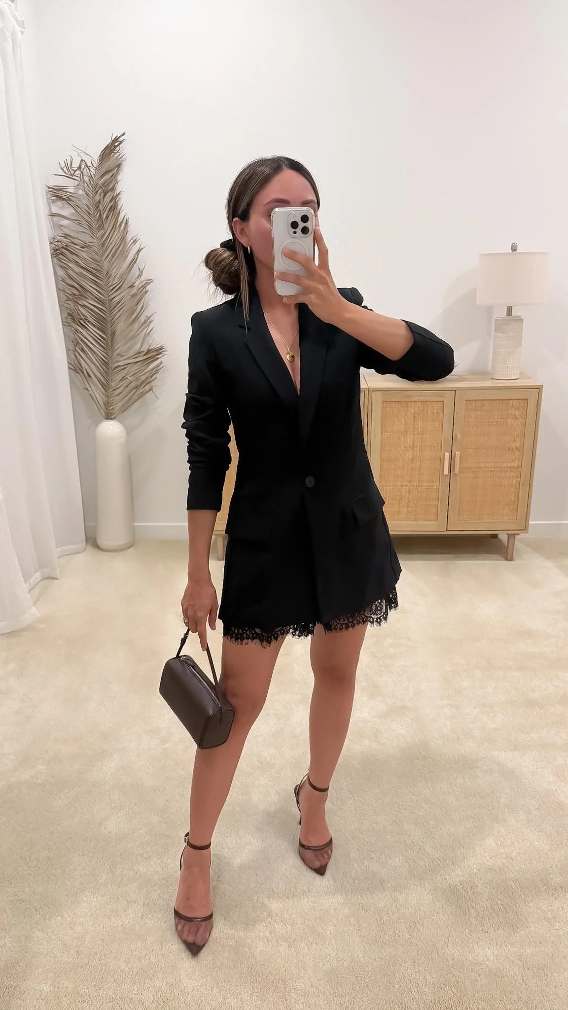 Long black blazer styled over satin lace shorts with brown heels for an elegant fall outfit.