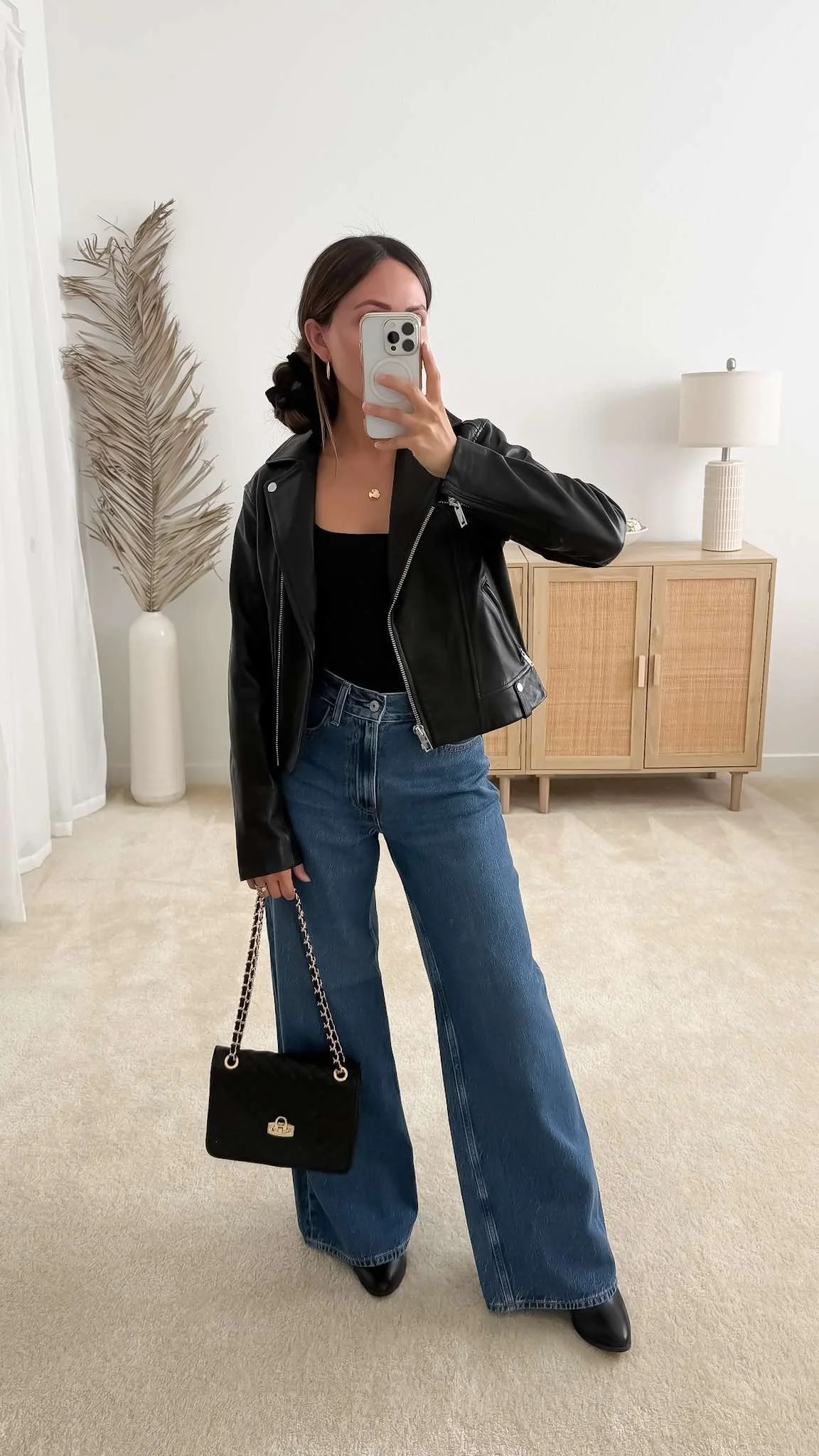 Casual fall date night outfit with a black leather jacket, tank top, wide-leg jeans, ankle boots, and a quilted chain-strap bag