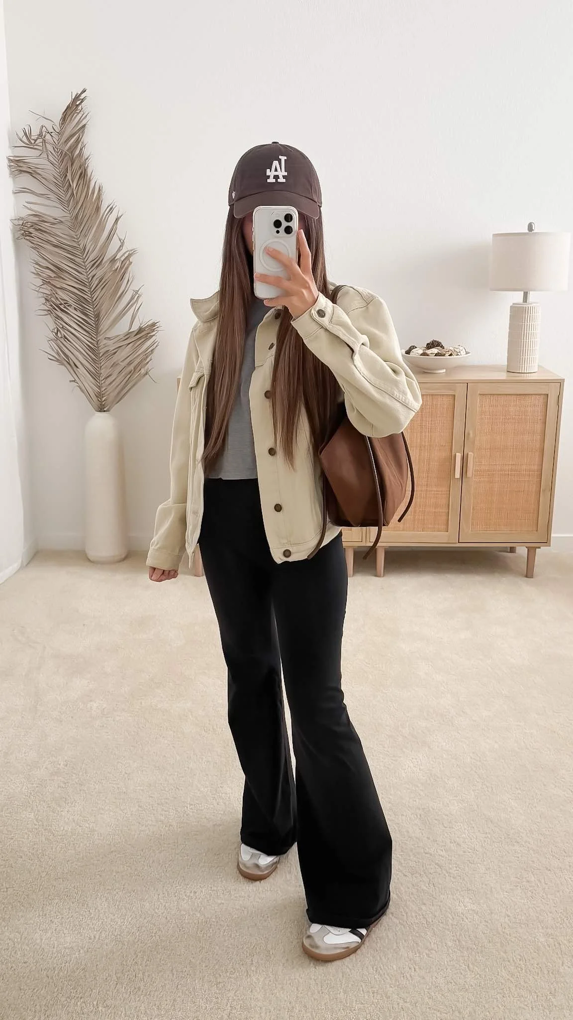 Beige denim jacket layered over a gray T-shirt with black pants and white sneakers for a casual fall outfit.