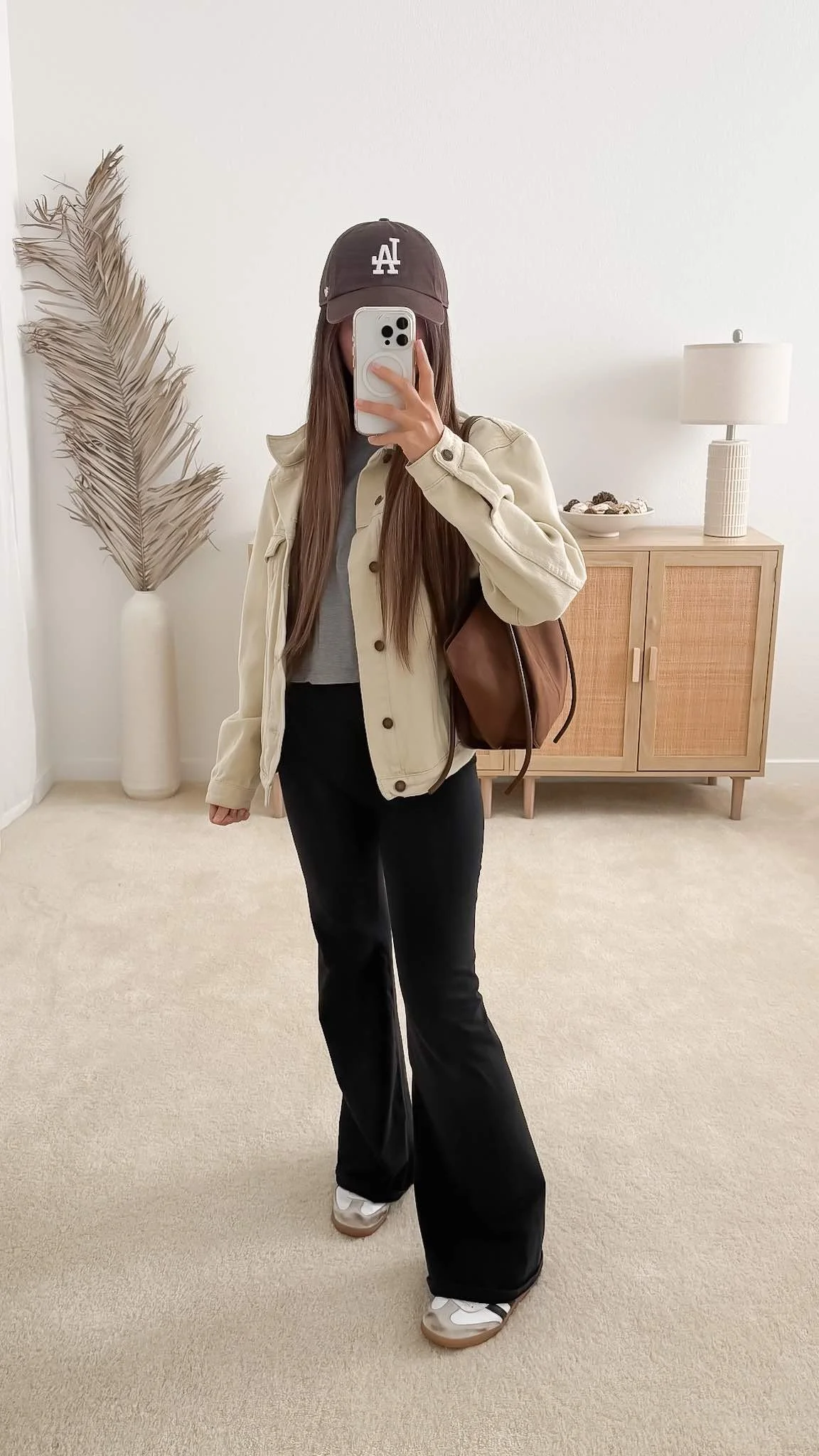 Early fall outfit with black flared leggings with a cropped T-shirt, lightweight beige jacket, and sneakers