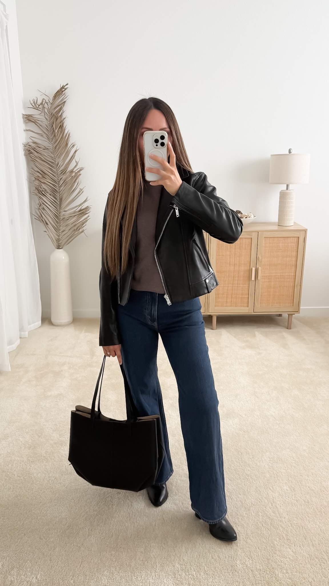 Casual fall date night outfit with a black leather jacket, brown sweater, dark-wash jeans, pointed ankle boots, and a leather tote