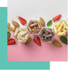 Assorted white, mocha, and chocolate candies in hexagonal containers surrounded by strawberries, almonds, and mint leaves on a pink and white background.