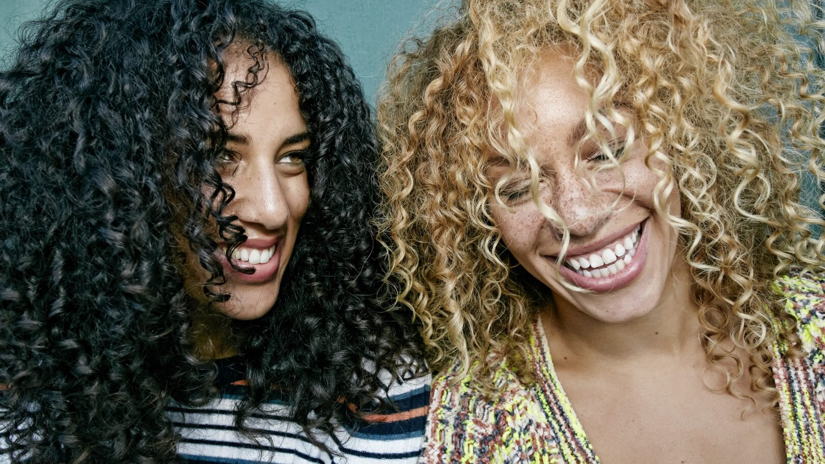 portrait_of_two_young_women_with_long_curly_black_and_blond_hair__smiling_and_laughing_-1620x911.jpeg