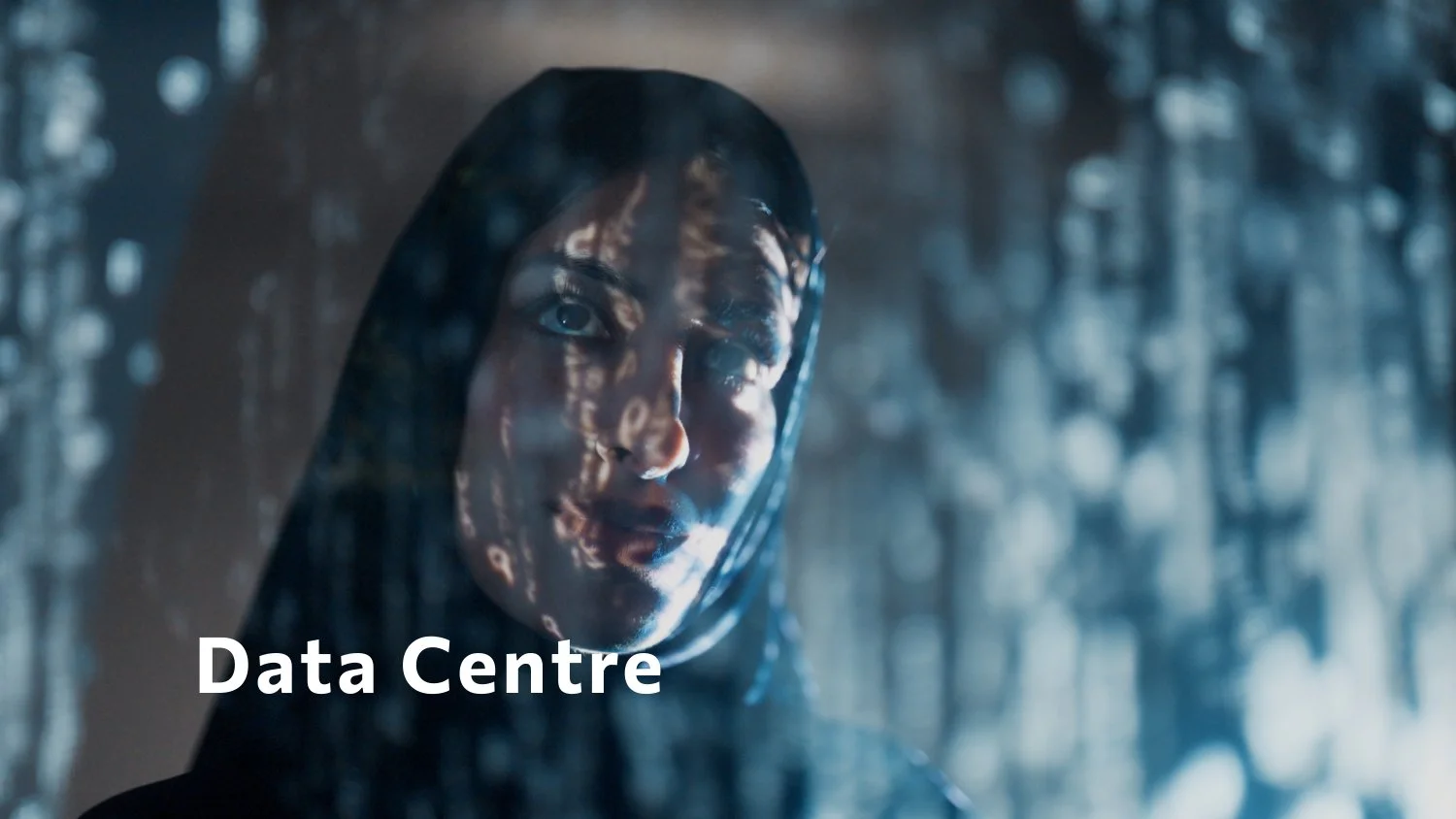 A woman's face behind a glass window with reflections and the words 'Data Centre' in front.