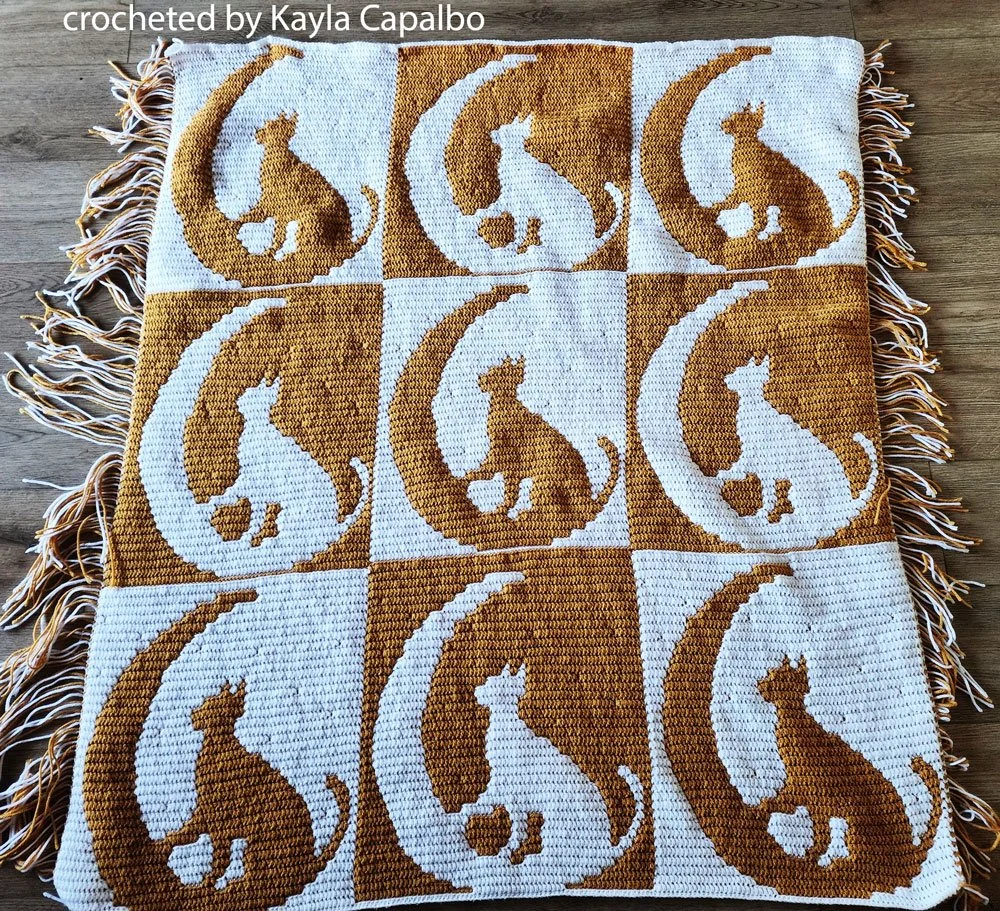 A beautifully crocheted mosaic afghan featuring nine cat silhouettes sitting under crescent moons.