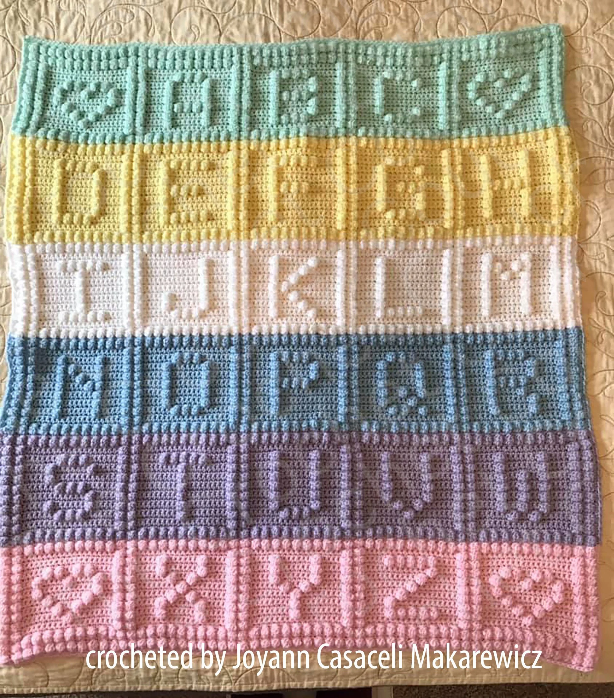 A colorful crochet baby afghan made with bobble stitch, featuring the alphabet A-Z.