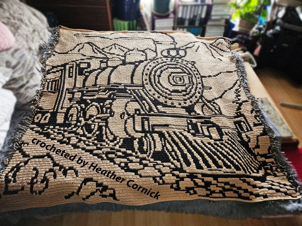 Black and white mosaic crochet afghan featuring a detailed steam locomotive design with mountain scenery in the background.