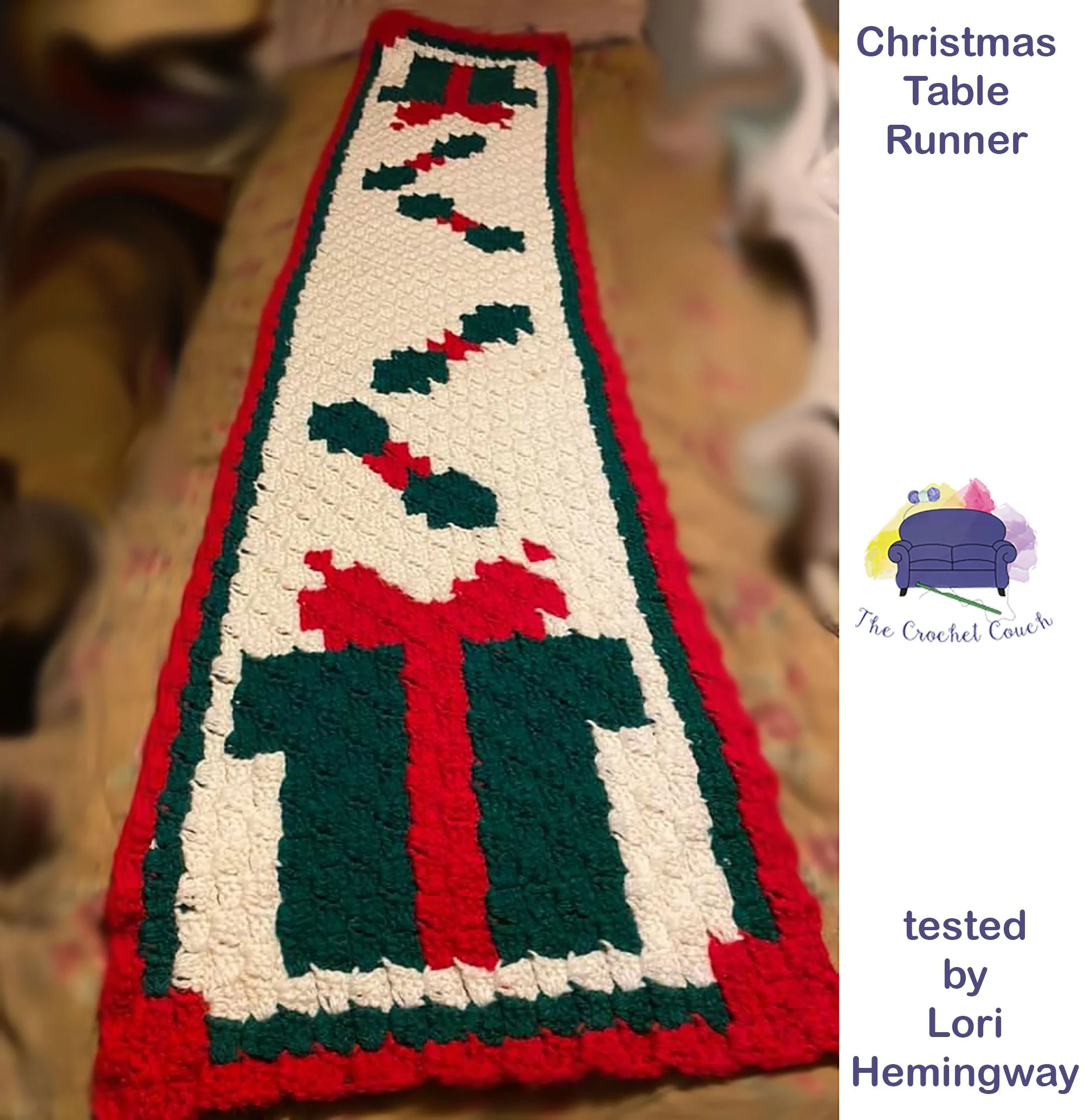 Holiday Table Runner shown on a table, crocheted using corner to corner in white, red and green.   The ends of the table runner each have a gift and some holly.  Crocheted by Lori Hemingway