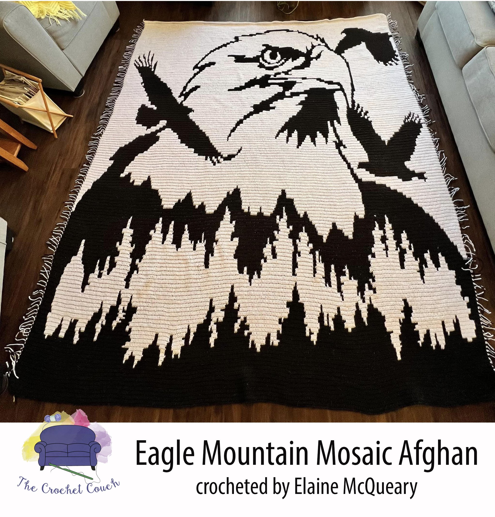Crocheted afghan laid out on floor.  Afghan is done in black and white and shows an eagle head with eagles flying around and the fades into mountains with trees.