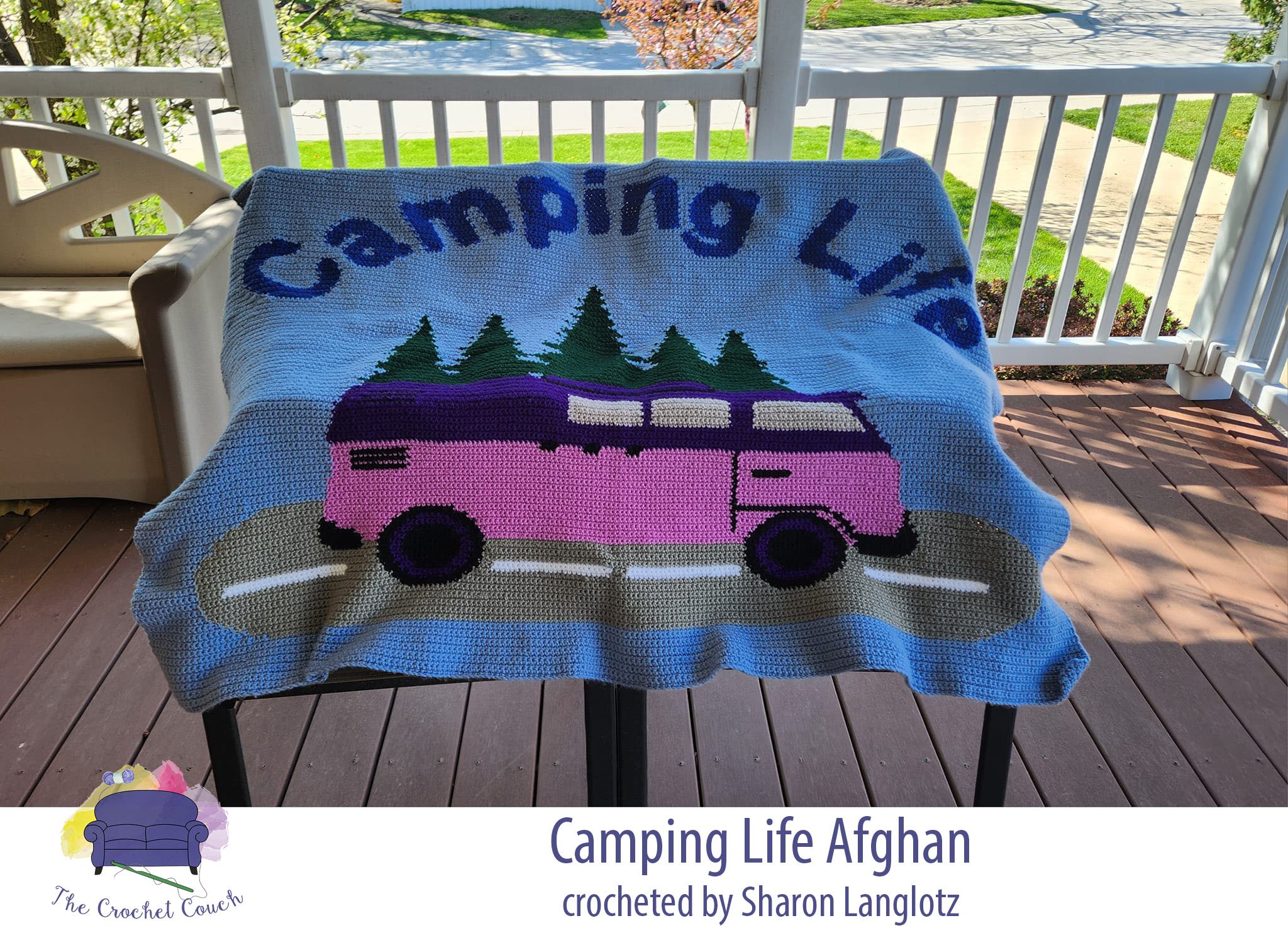 Crocheted afghan shown laid outside on chairs.  Afghan depicts a pink camper driving down the road with trees in the background and it says Camping Life.