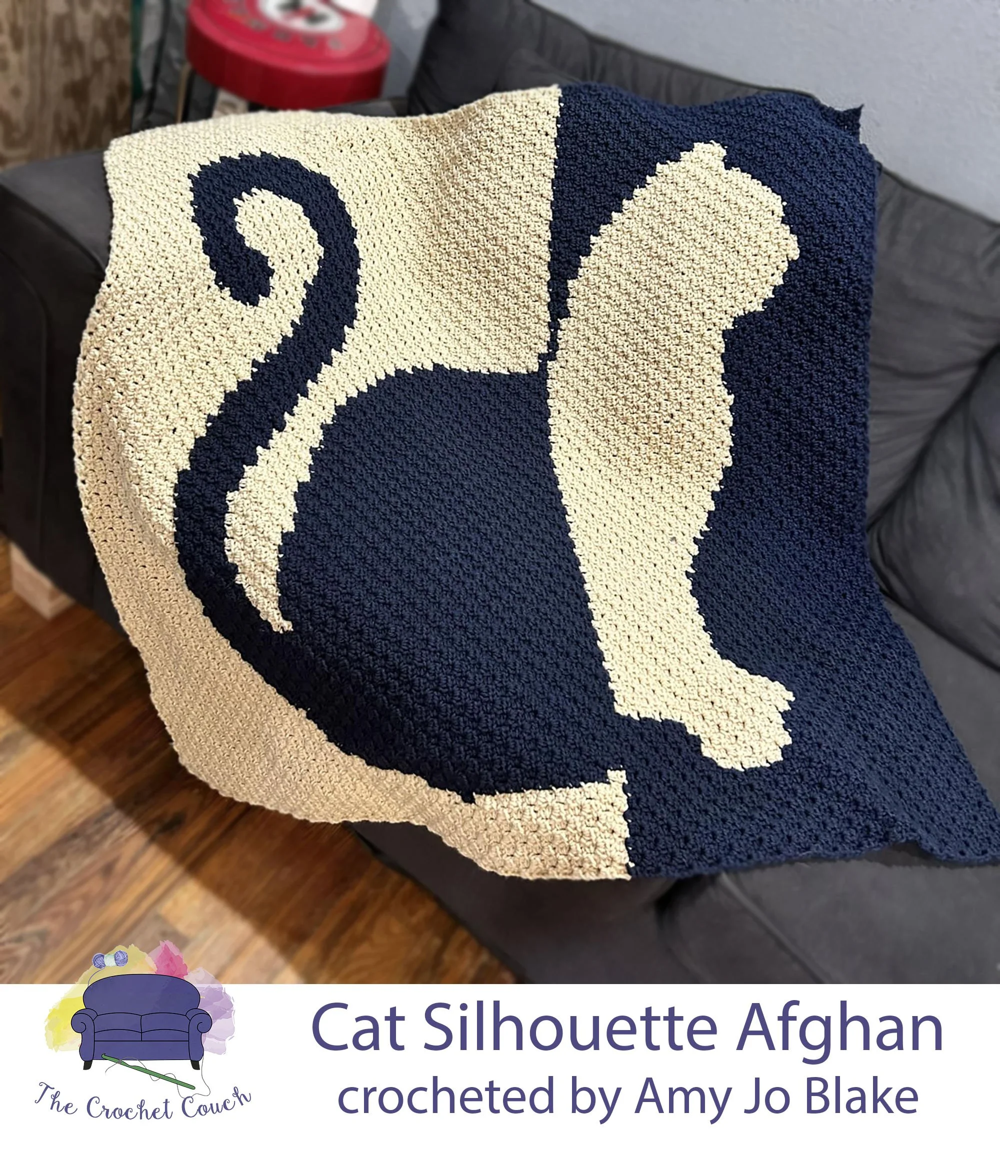 Crocheted afghan is shown laying on couch - depicts a two tone cat silhouette done in navy and off white, using the C2C and crocheted by Amy Jo Blake