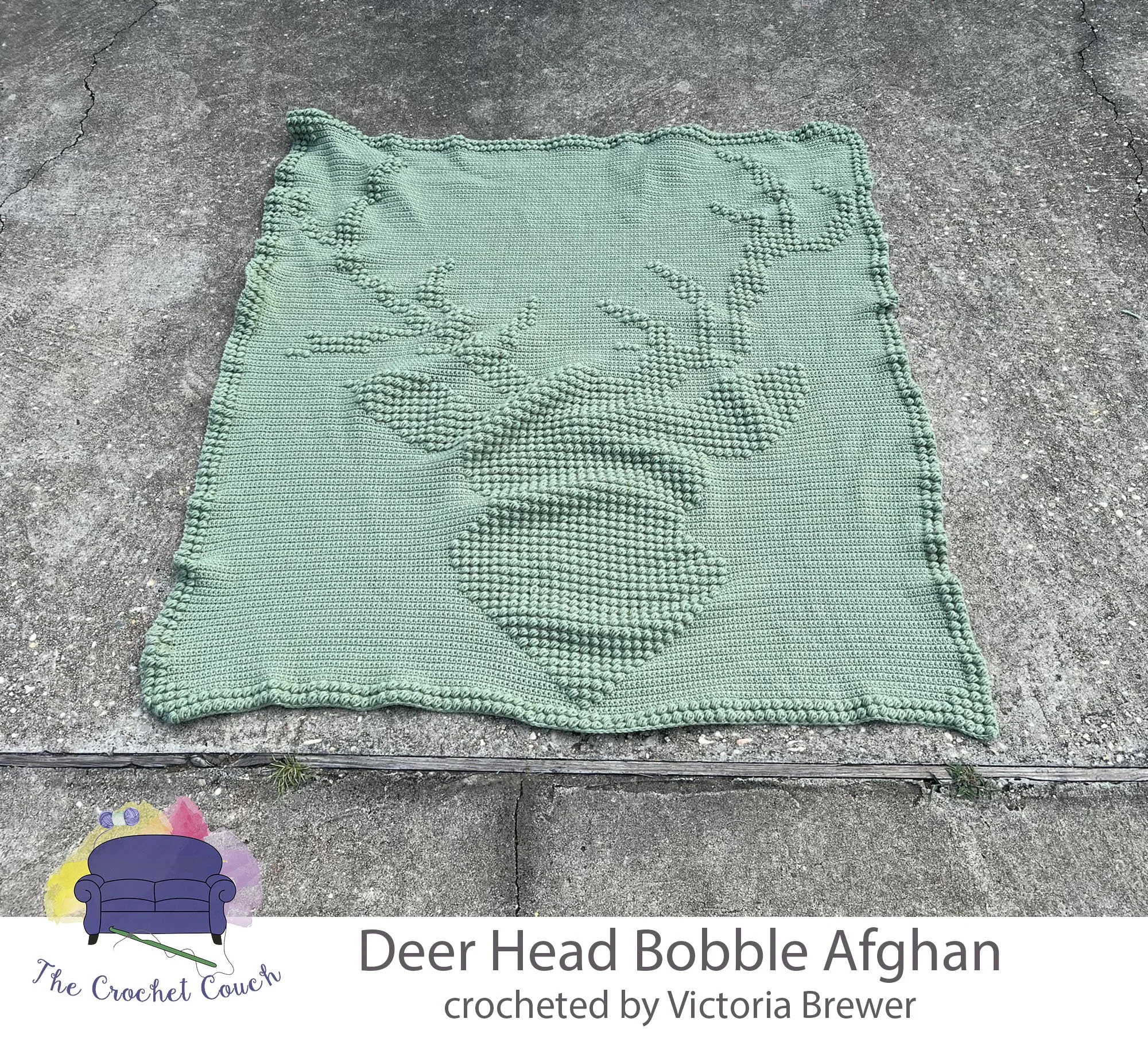 Crocheted afghan shown laying on payment and done using the bobble stitch in a frosty green color. Bobble form a deer head with antlers. Afghan was crocheted by Victoria Brewer