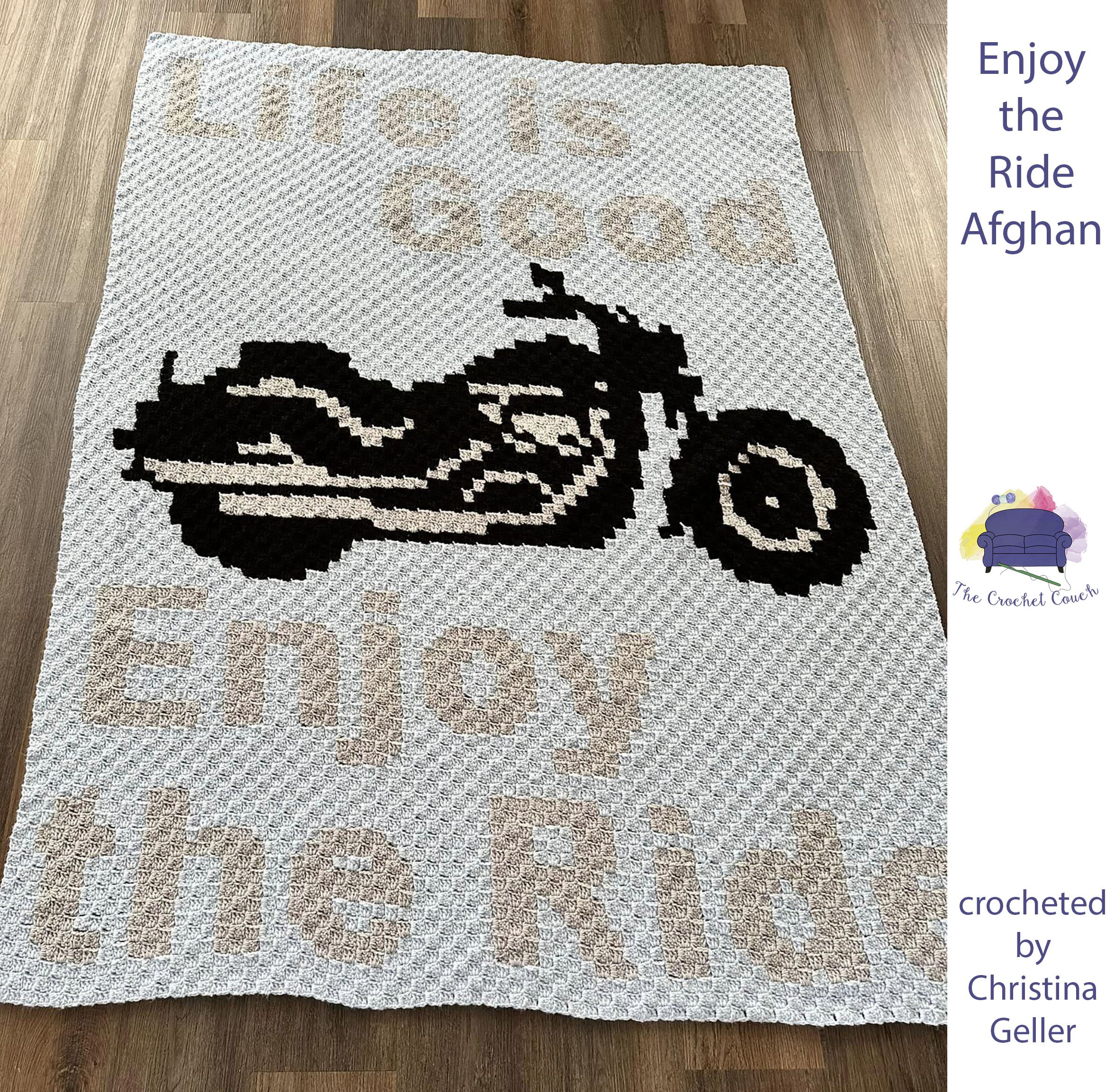 Crocheted Afghan shown laying on floor - depicts a motorcyle with the saying, “Life is Good, Enjoy the Ride”.
