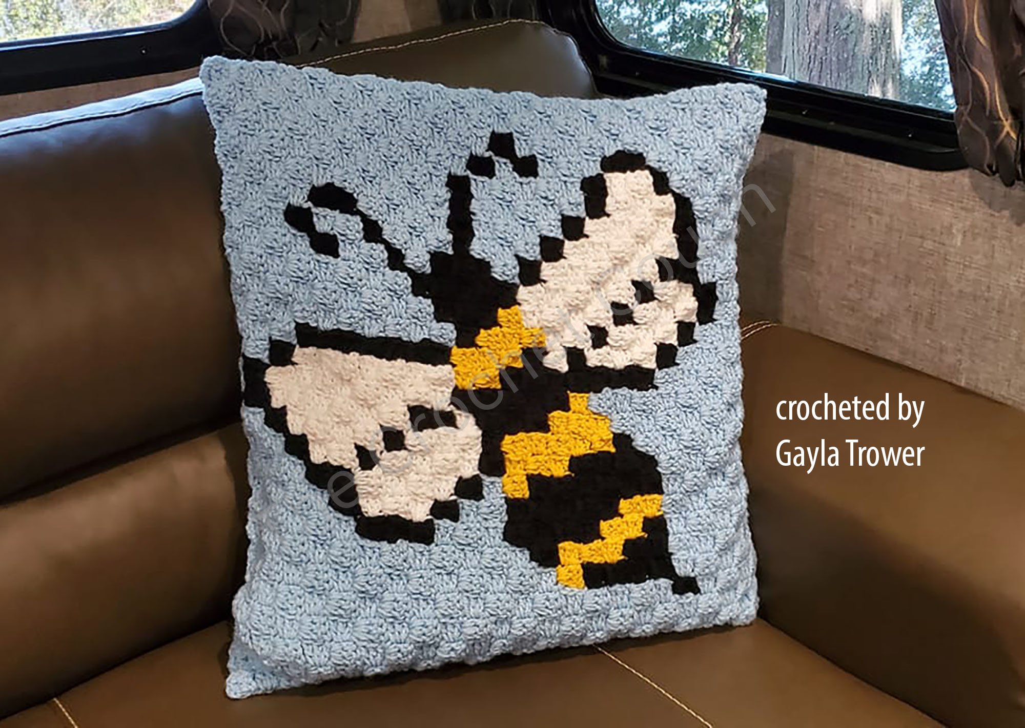 Crochet bee pillow with blue background, black and yellow bee, made using the corner-to-corner technique.