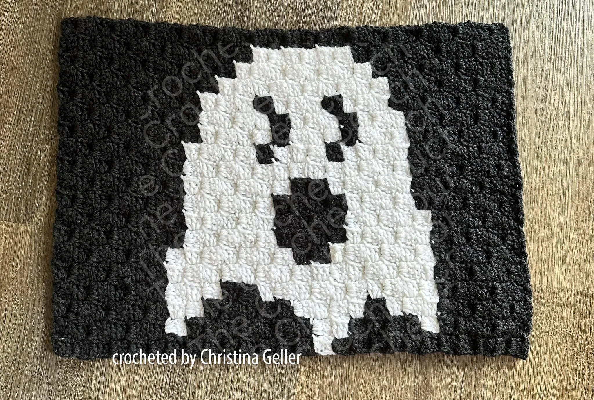 A crocheted placemat featuring a white ghost on a black background