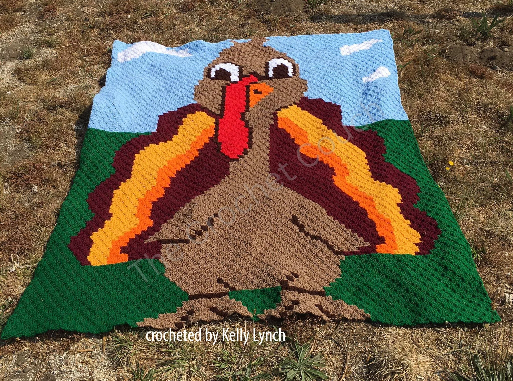 A colorful Turkey Tom crochet afghan featuring a cheerful turkey with vibrant feathers set against a nature-inspired background.