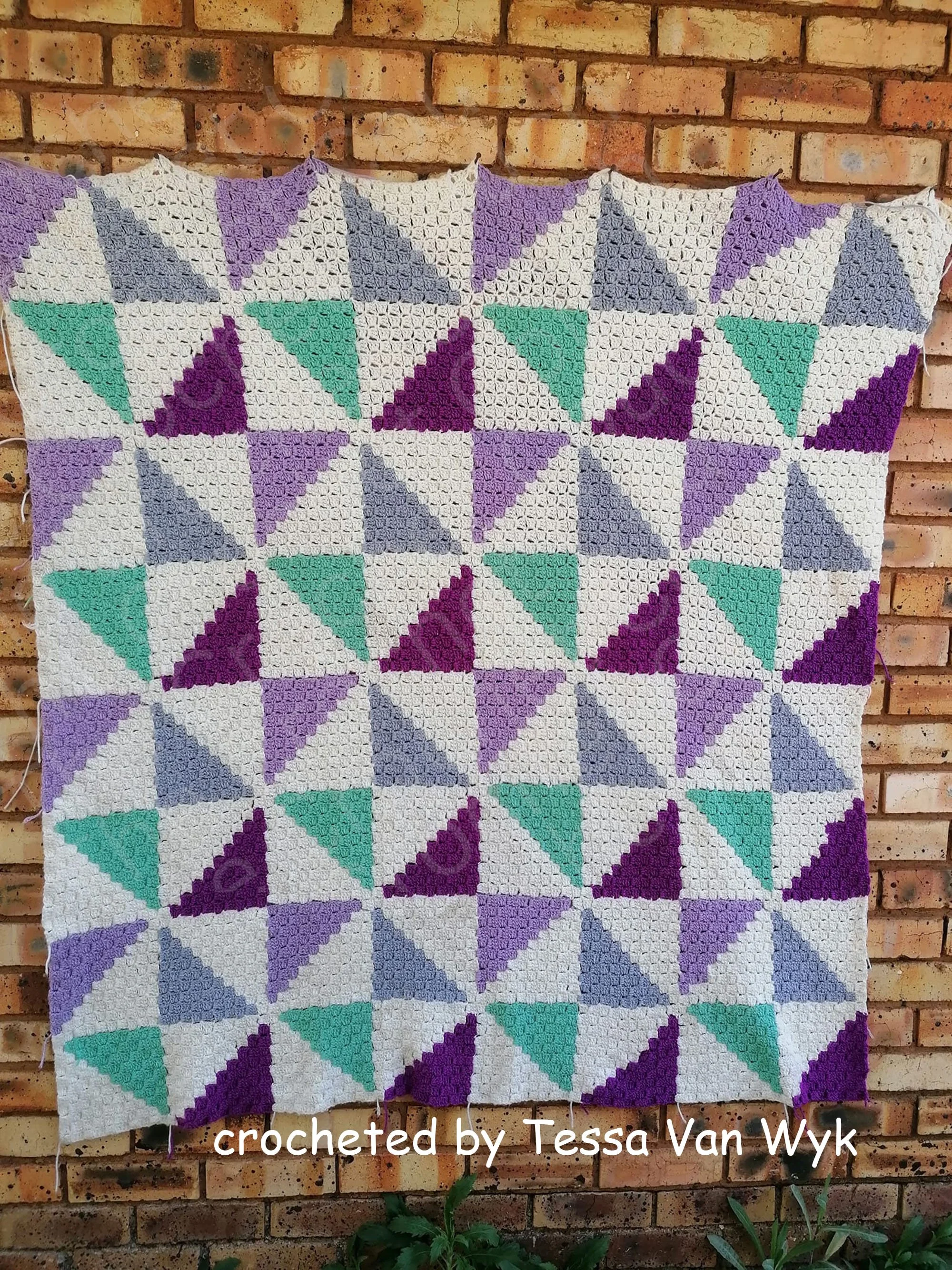 Geometric crochet afghan in purple, teal, and grey, featuring corner-to-corner triangle squares.