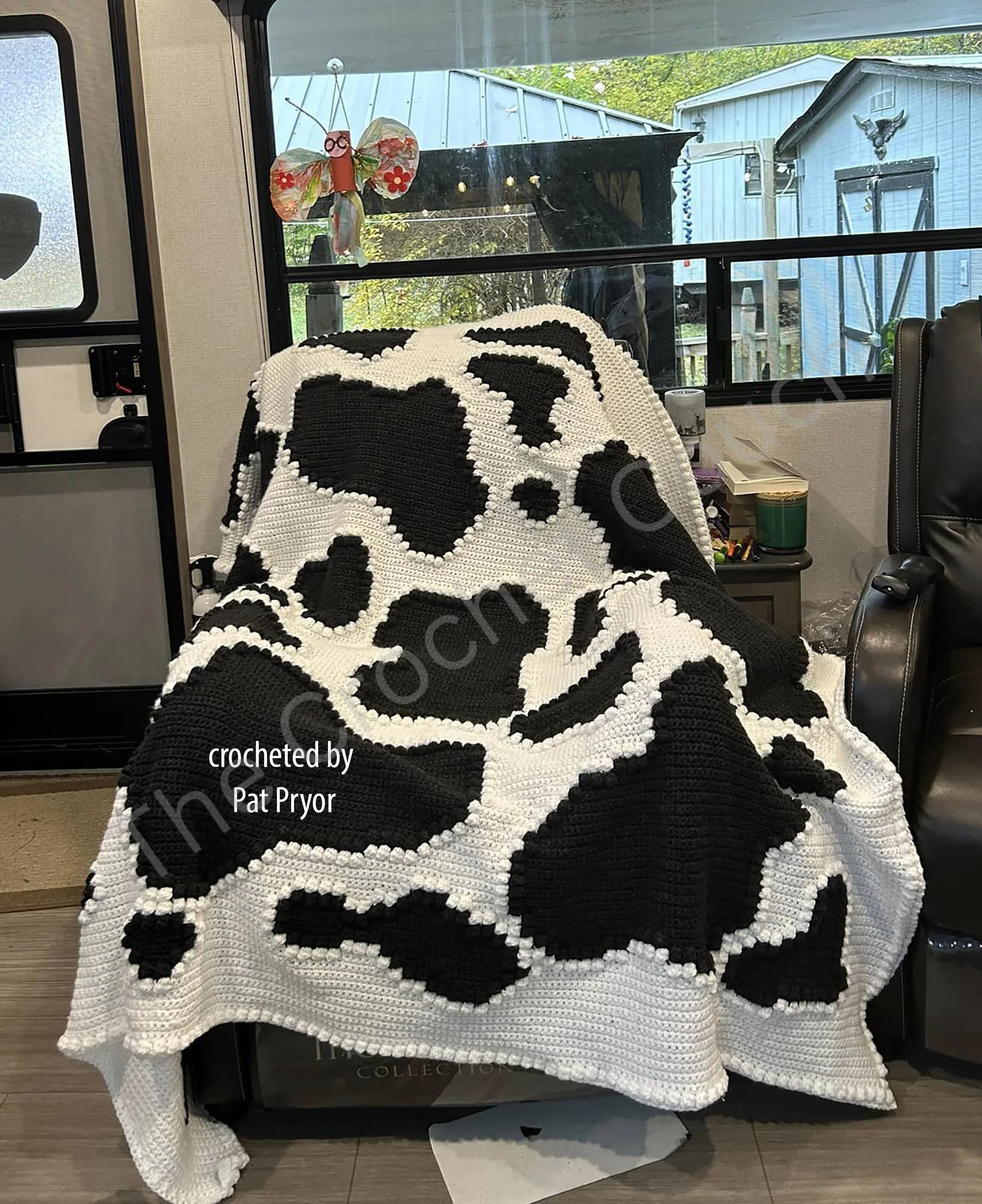 Crochet afghan featuring a black and white cow print design with textured bobble stitches.