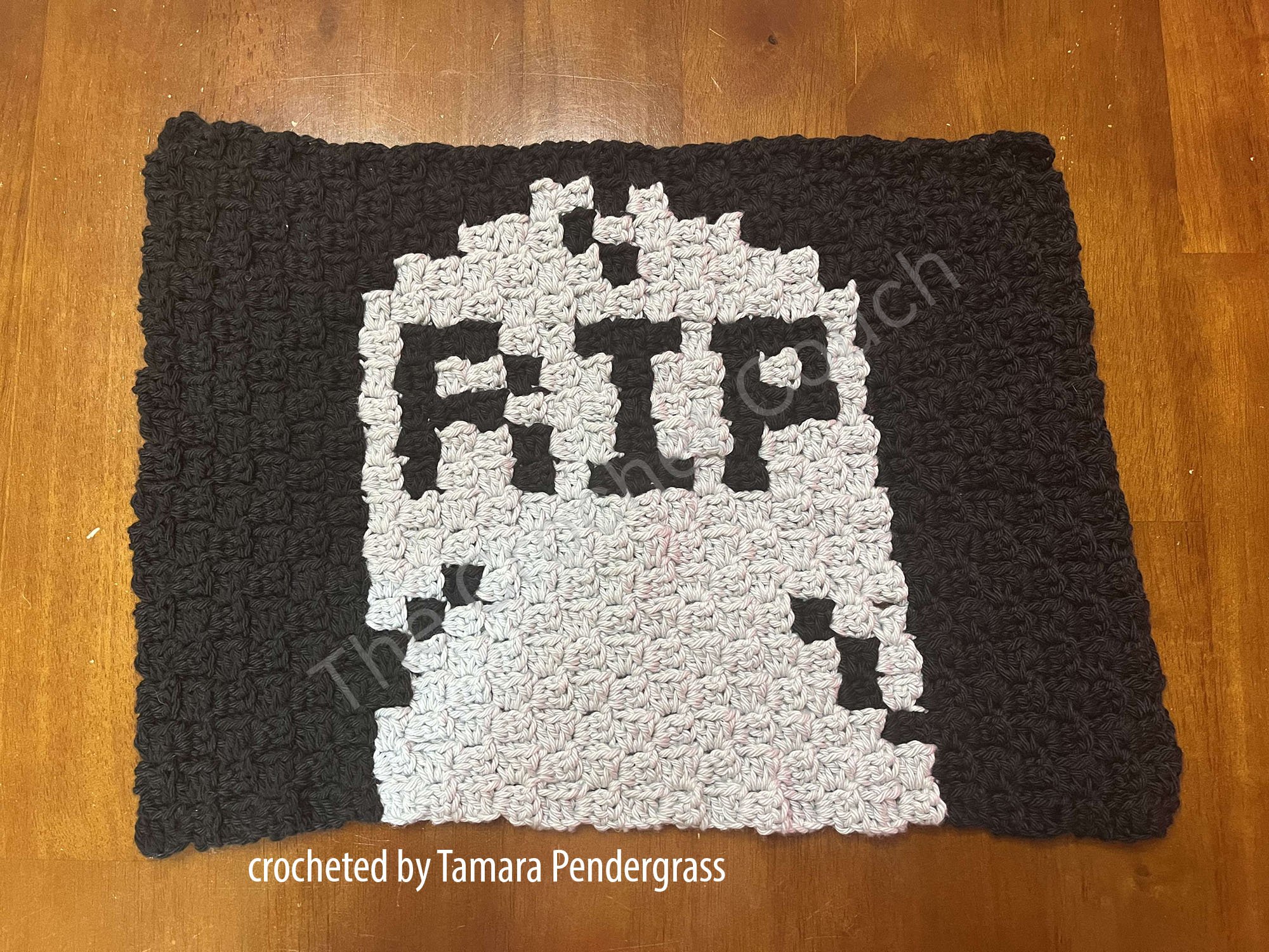 A handmade crochet placemat featuring a gray gravestone with the letters "RIP"