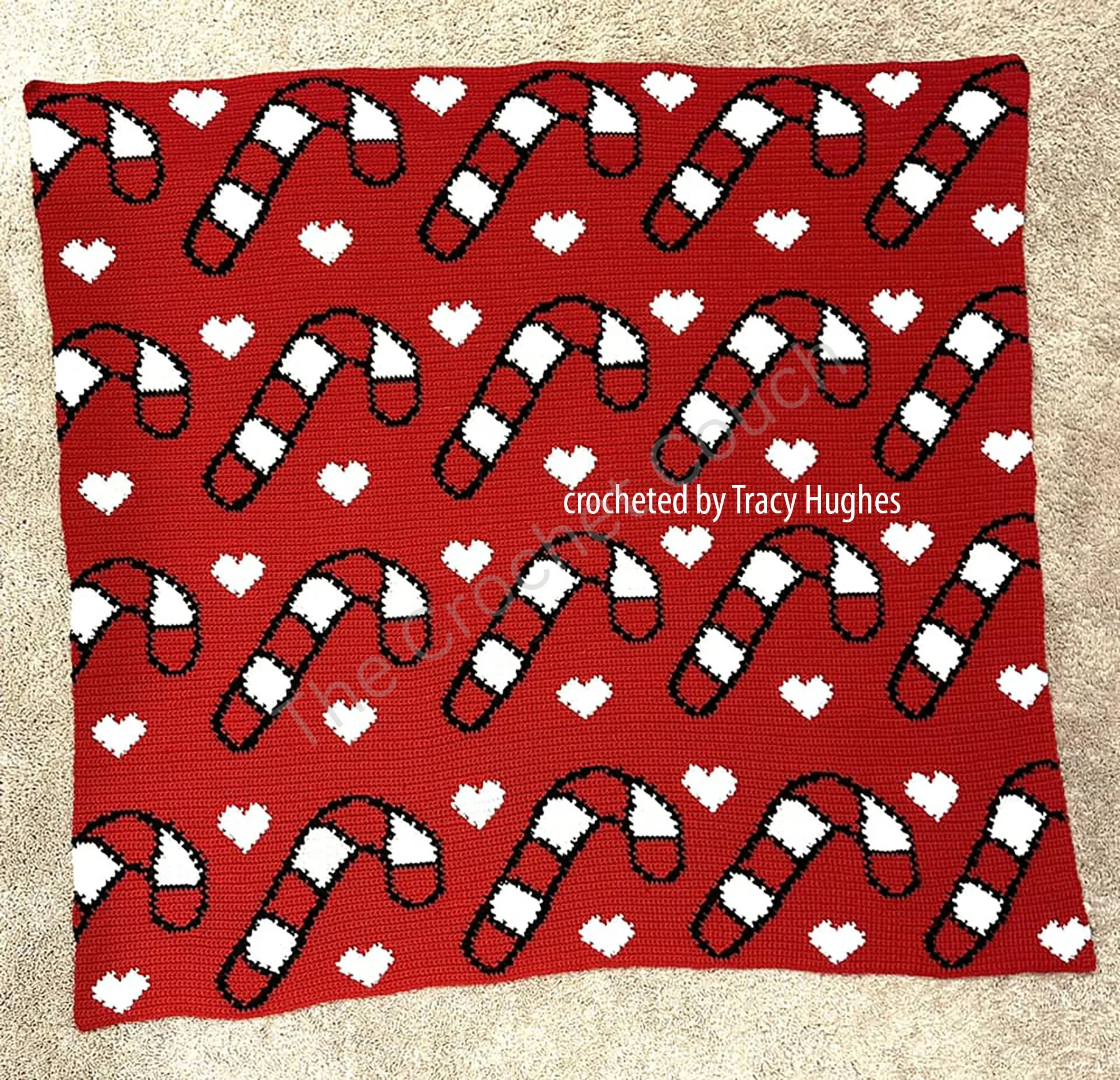 A cozy red crochet afghan featuring a repeating design of white candy canes and hearts. The festive pattern creates a bold and cheerful look, perfect for holiday decorating or gifting.