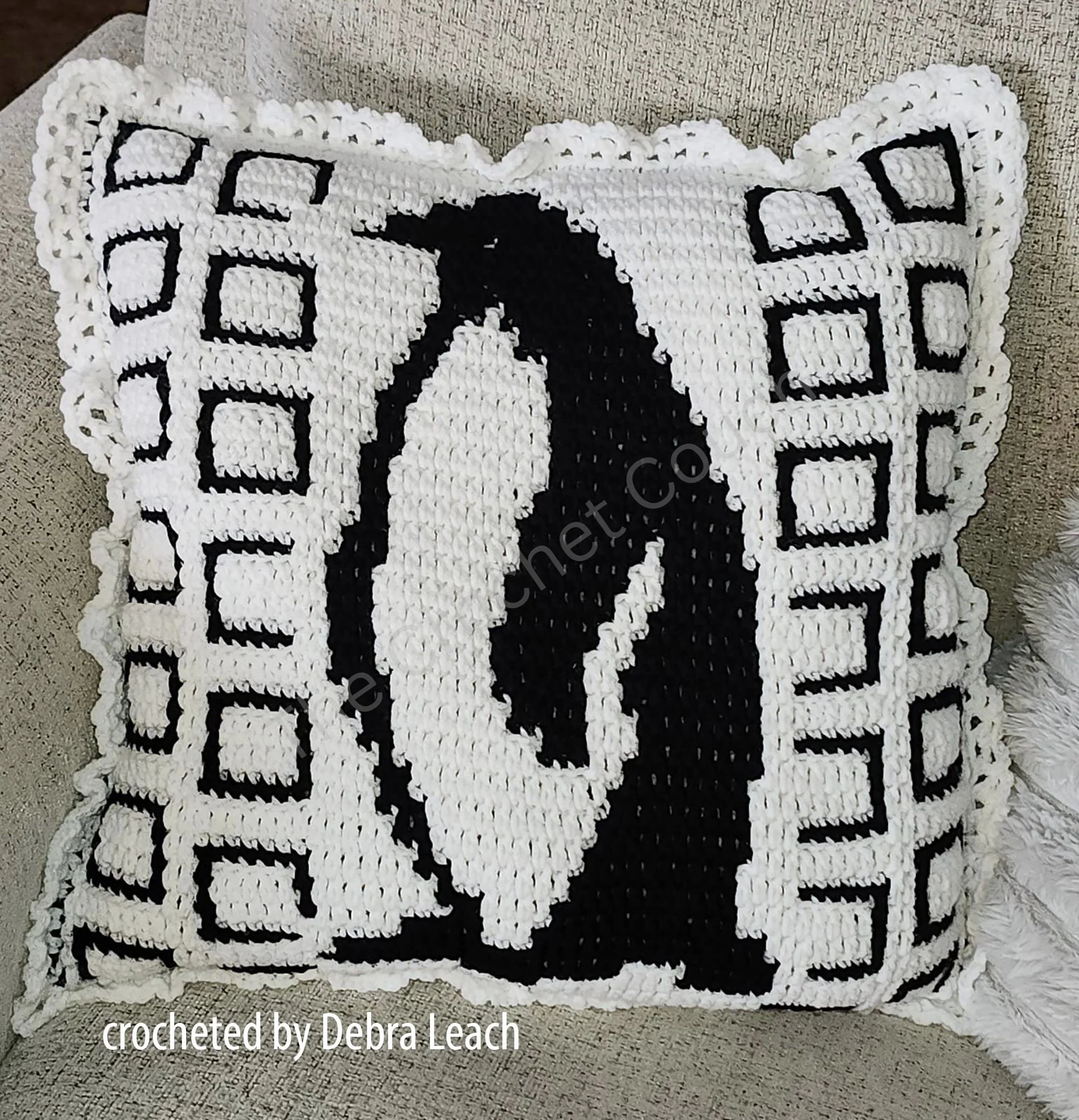 Image of a crochet pillow with a black and white penguin design