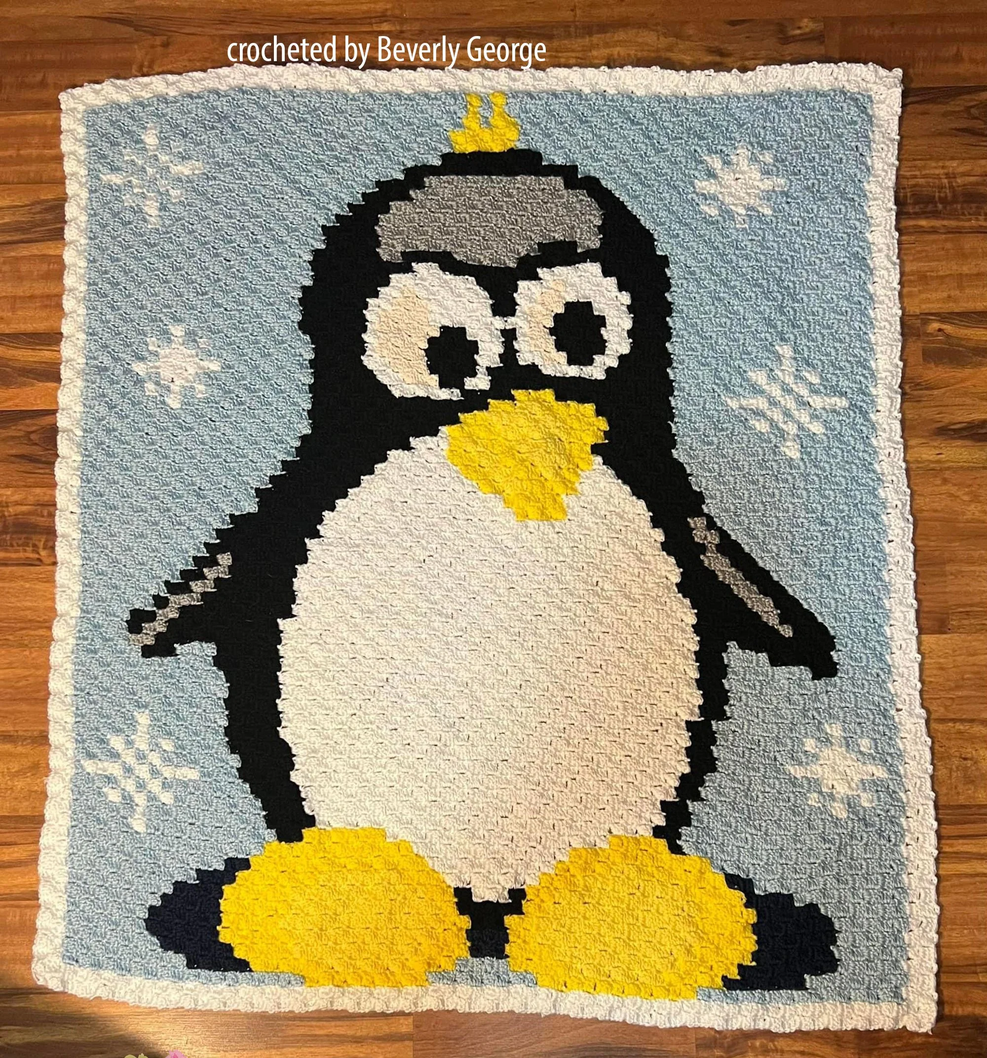 A handmade crochet afghan featuring a cute black-and-white penguin